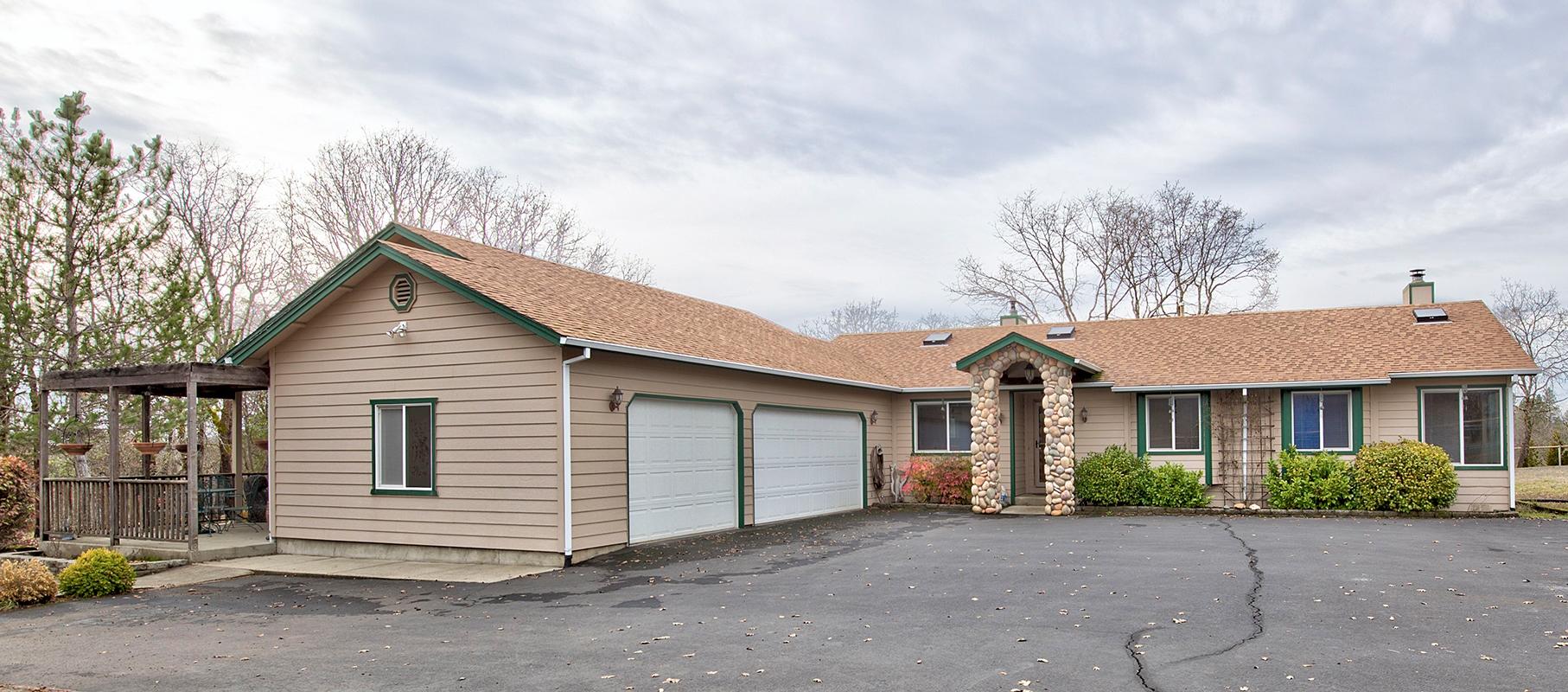 Here is a home in a country setting not far from local amenities. This 2,400+ sq.ft. home with finished, 3-car garage on 2.53 acres has a lot to offer. Spacious master bedroom and bath with romantic fireplace and personal deck overlooking the serene backyard. Plenty of room to entertain in the family room, recreation room, dining room and open kitchen area while keeping cozy next to the woodstove. Host terrific BBQ's on the back patio and covered porch area with easy access to the kitchen. One wing of the home is suitable as a  second living area for guests with with its own private entry, bedroom, bathroom, kitchenette, and porch. Additionally, a commercial kitchen is set-up and equipped and was previously certified. Flat land and plenty of space to create your own Oregon paradise while enjoying the mountain views surrounding the home. One-year Home Warranty included with purchase.