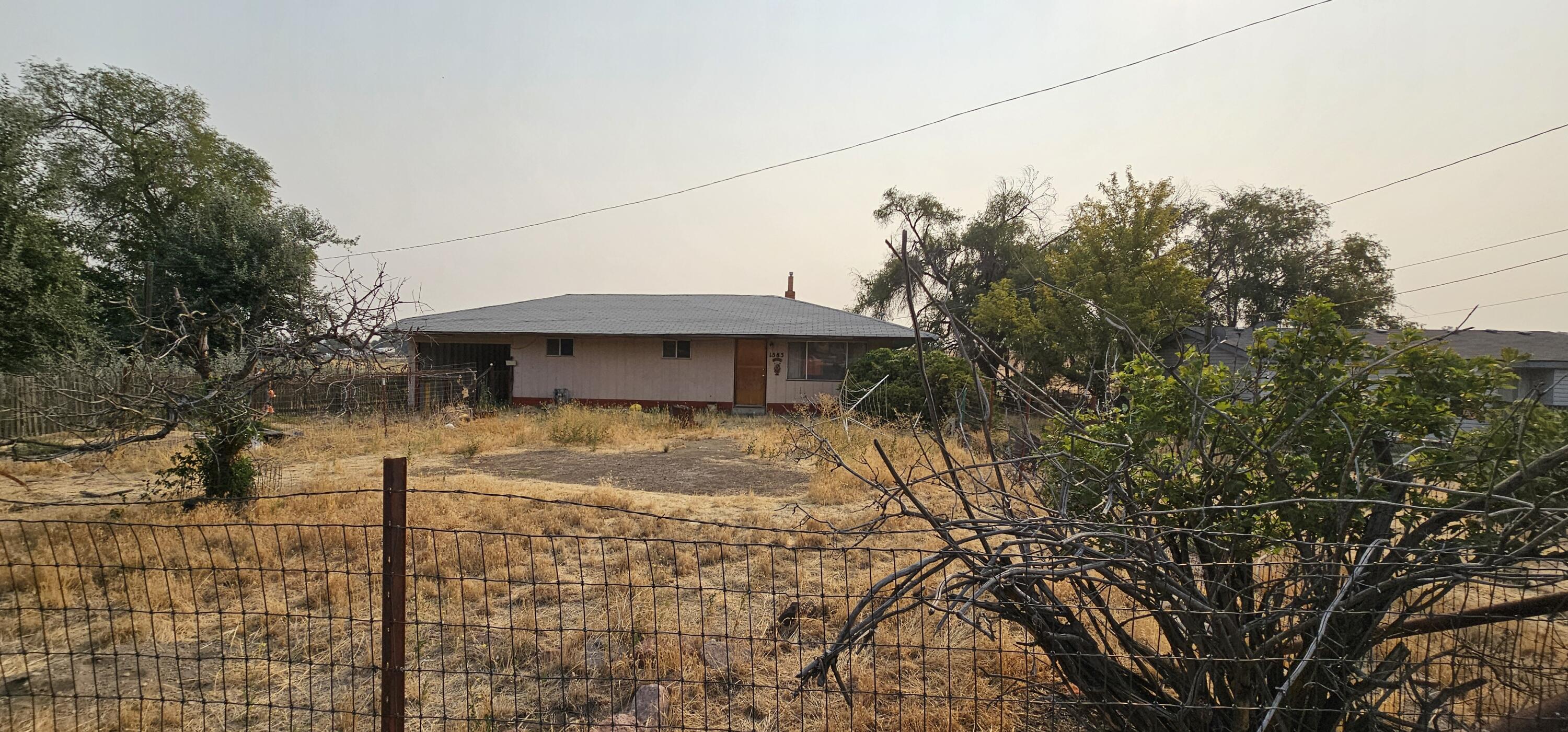 Investor Special - 3 bedroom 1 bath, 1566 sq ft 1962 built home currently on .23 of an acre.  There is an attached shop with rolling doors to the carport.  Part of the 1566 sq ft includes a huge playroom.  This is an estate sale and the home is being sold in as is condition.  The home has been vacant for 10+/- years.  Water has been off since 2021, power was shut off in May of '24 and natural gas is still on.  Owner Will Carry with substantial down and agreed upon terms.  Home is attached to a dry well shared by the property to the south for septic.   Possible sewer hookup soon.  Seller will record an easement for use of dry well between the properties. Seller to do a survey to locate property corners prior to closing.  Property size and southern boundary could vary slightly when survey is complete.