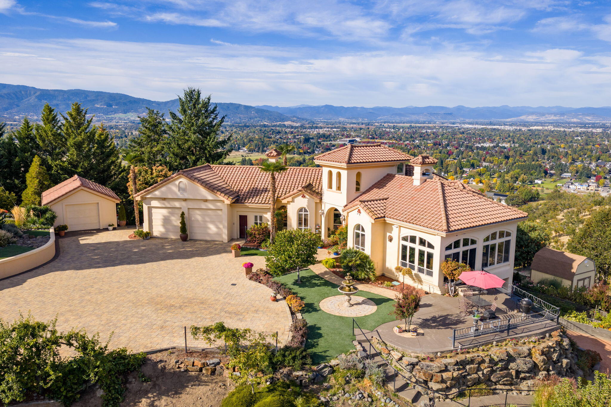 Just Listed! Amazing Northwest Santa Fe style home perched on a knoll w/forever views overlooking vineyards, valley, city lights & Mts. Paved driveway to 1.02 ac lot w/brick entrance wall w/dbl gated entry to paver courtyard w/3 car garage, stucco exterior, tile roof, palm trees & great landscaping w/night lighting + a lg water fountain. Lg front arched wood door w/covered area w/beautiful brick floors, Lg ceilings, archways niches, floor to ceiling windows to take the views! Many doors & French doors to beautiful cement patios off primary suite, great/family rm & dining rm. Downstairs 2 bdrms w/lg cement patio + a brick covered patio. Montana stone sitting area w/built-in fireplace. Amazing kitchen w/lg island, granite counters, Wolfe 6 burner gas cooktop & oversized convection oven perfect for entertaining. Beautiful primary suite, 2 walk-in closets, lg tile shower, soaking tub & French doors out to a covered patio. Many garden beds w/drip systems, greenhouse & whole house generator