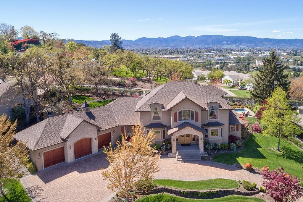 GORGEOUS custom home in serene location w/ exceptional quality, extras & amazing views yet in the heart of Medford convenient to all your needs! Exterior of stucco & sandstone from Idaho opens to 3 bed, 3 full & 2 half baths, 5649 sq ft of soaring ceilings, Italian Versace tile, hickory hardwood floors, honey dipped stained knotty alder woodwork & trim, 4 different fireplaces, abundance of windows for views and light & a floorplan that lends itself to large group entertaining or intimate, relaxing time for two. The gourmet kitchen is in the center of the home & allows easy preparation of your favorites while still visiting with friends & family. Main floor living w/luxurious master suite, laundry, private den/office, great rm, formal & informal dining & easy access to outdoor fp living, pool, waterfalls, gardens & Views. Upstrs boasts 2 guest suites,2nd office & another living/pool table, bar area w/2nd outdr living VIEW area. Main flr closet for future elevator to 2nd flr. 3 car gar.