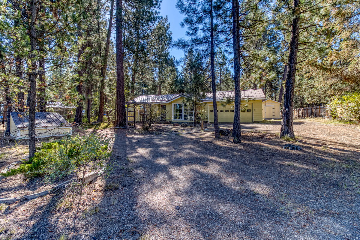 This cozy, two-bedroom, one-and-a-half-bath home sits on over an acre of wooded land, offering a serene, private retreat with easy access to adventure. A circular drive fronts the stick-built house, which features a sunken living room with a bay window and a cozy wood-burning stove set into a floor-to-ceiling brick fireplace. The efficient kitchen includes a breakfast bar and an eating area with a garden door opening to a Trex deck, perfect for enjoying the deep, forested backyard. The attached garage provides a workbench and storage, while a separate, oversized detached garage offers ample space for a workshop or storing recreational vehicles. This property is minutes from La Pine State Park, Deschutes National Forest, numerous Cascade lakes, and the multitude of outdoor activities the area is known for, from fishing and skiing to hiking and water sports. It is also just a short drive from La Pine, Oregon, for convenient shopping and services. Make this your home for the Holidays!