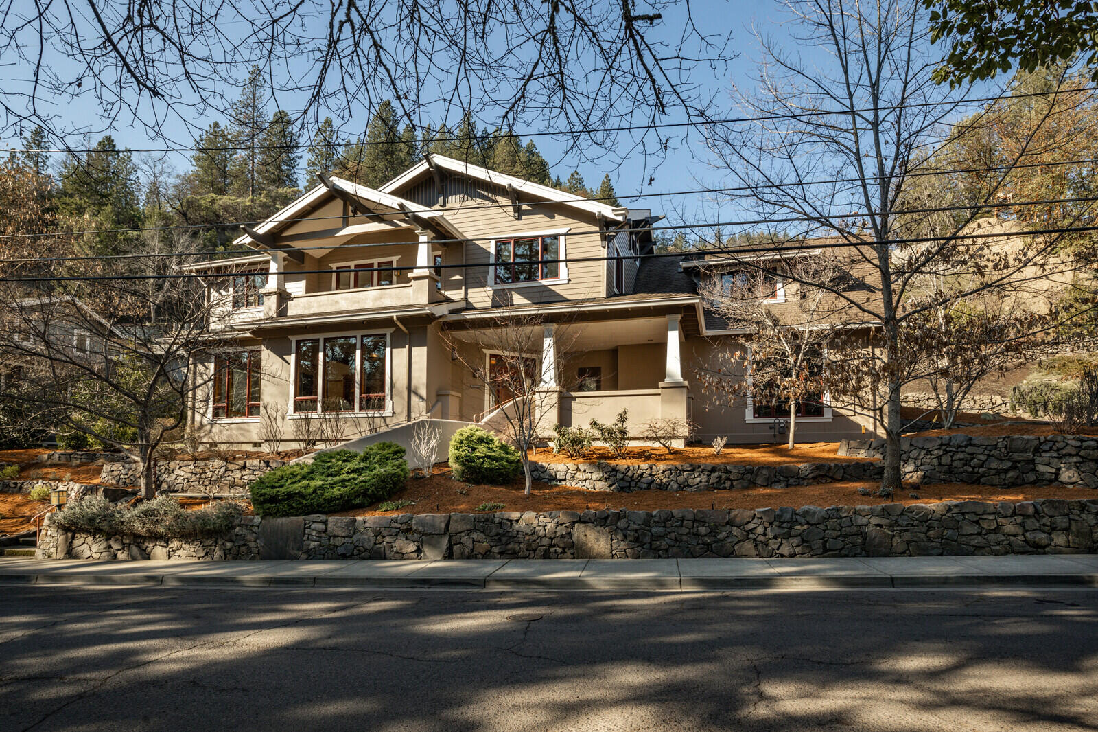 Sitting on Ashland's most sought after street, this gorgeous contemporary Craftsman home overlooks Lithia Park and its upper duck pond while being just blocks to the Plaza. It also sits at the foot of Ashland's extensive trail network, making this an unbeatable location. This stunning home features hardwood floors, three fireplaces and custom doug fir built-ins throughout. The chef's kitchen has a large island, stainless appliances, including a wine fridge. The great room has double height ceilings- filled with natural light. A dedicated movie room rounds out the living space. Upstairs (via stairs or elevator) has an amazing primary suite with fireplace, three additional bedrooms, two ensuite- one a perfect in-law set up with a separate entrance. Lovely landscaping, mature trees, an outdoor fireplace and a swim/spa all add to this amazing property. This is a must-see home!