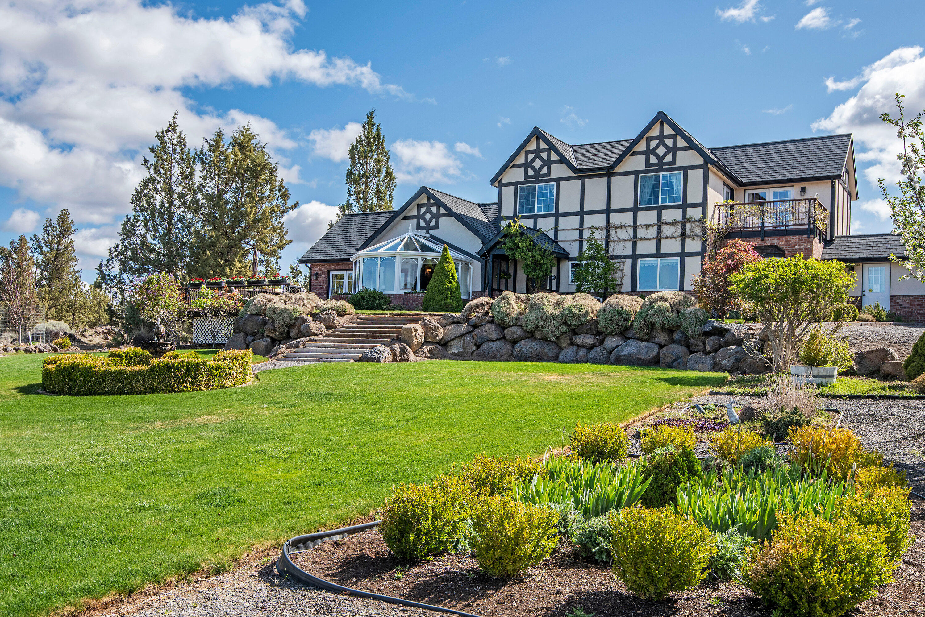 This true English Tudor home sits on 5+ acres in the Tumalo area with panoramic Cascade Mountain views from Mt. Bachelor to Mt. Jefferson. The grounds are impeccably maintained and include a large fenced vegetable garden with several varieties of berries. The 3,040 sq. ft. home features quality finishes throughout, a large main level master suite with gas fireplace, and a large gourmet kitchen. There is also a conservatory, bought and shipped from England to take advantage of those amazing views, a 240 sq. ft. shop/office space off of the oversized garage, and an unfinished bonus room over the garage. In addition, there is a 1,360 sq. ft.  shop with a 40' deep RV bay with a 14' garage door, and 2 additional bays.