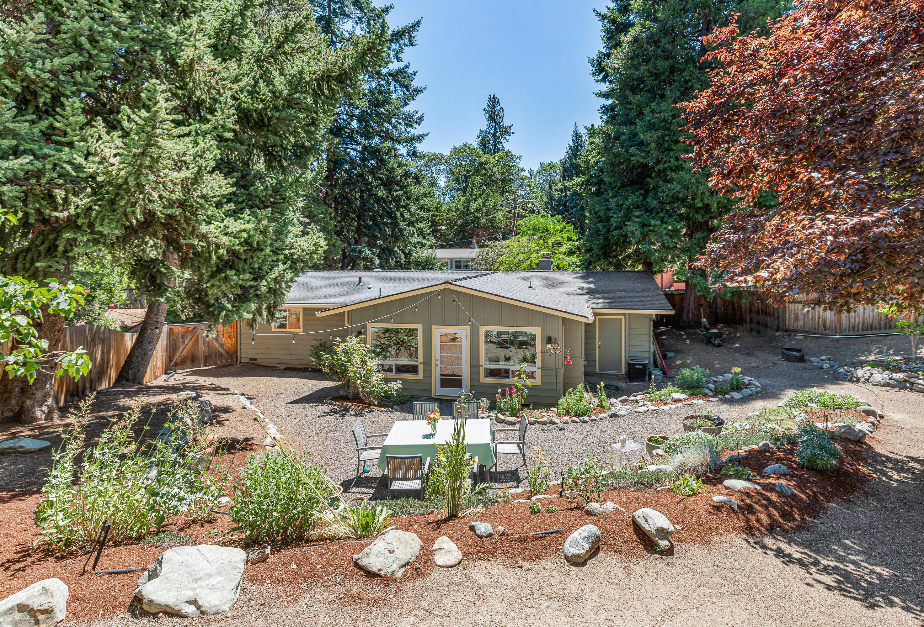 Updated single-level home on a spacious lot with mature landscaping extending up to Courtney Street; located in a desirable neighborhood above downtown Ashland with nearby access to public trail networks and Lithia Park. Features include oak and bamboo flooring, large double-paned vinyl windows, wood-burning fireplace with painted brick surround and tile hearth, open-concept living and dining room addition completed by reputable local contractor Milo Shubat in 2008 with vaulted ceiling and patio access, adjacent kitchen with granite counters and stainless appliances including gas range, three bedrooms, one full bathroom with tiled tub/shower combo, laundry room, and a one-car garage. Super private backyard with meandering pathways, patio, extensive stone terracing, and sunny gardening areas. Inquire with agents for additional details on improvements and upgrades by current and previous owners!