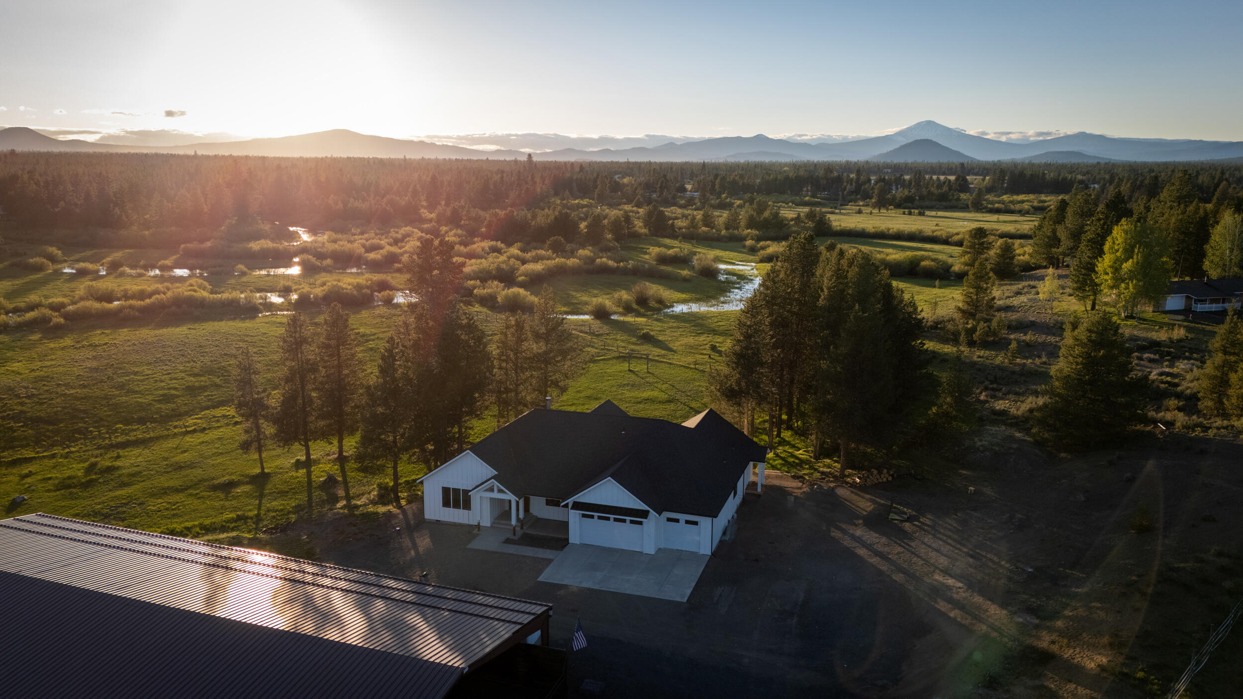Stunning 10-acre horse property with panoramic Cascade Mountain views and 564' of river frontage. New custom-built 2,941 sq ft home features 4 bedrooms and 4 baths, vaulted ceilings,  floor-to-ceiling stone fireplace. Gourmet kitchen is equipped with custom walnut cabinets, quartz countertops, professional-grade propane appliances. The primary suite offers a walk-in shower, dual shower heads, rainhead, smart bidet, coffee/tea station, and a built-in fireproof safe in the closet. Smart home features throughout. Additional highlights include a walk-in pantry, mudroom, and zoned heating separating the main living quarters from the guest suite. The Guest Suite has separate entrance, bedroom, bath, kitchenette, living room, and laundry area. Comfort is ensured with a whole-home automatic backup generator. 7,200 sq ft Red Iron Barn includes a 60x90 riding arena,30x60 enclosed area for stables, tack room, or convert into a shop. Experience the proximity to Central Oregon recreation.