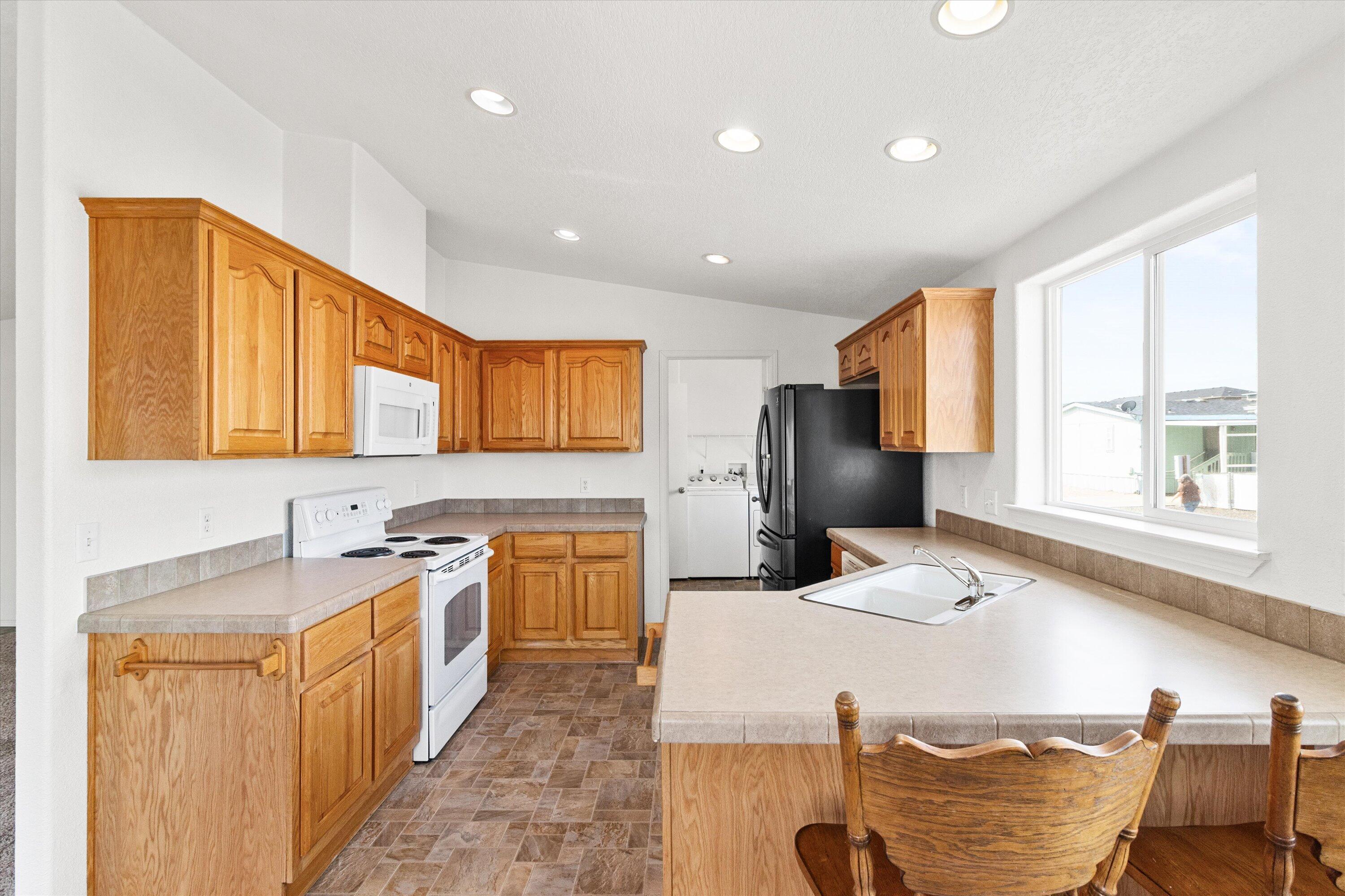 Lower-than-average space rent at just $625/month, plus the seller is offering three months of space rent to help make your move easy. Designed for ease of living, this 2-bedroom, 2-bath, 1,296 sq. ft. home features step-free entry, accessible ramps, and wide walkways, eliminating the cost and hassle of retrofitting. The kitchen offers warm wood cabinetry, a breakfast bar, and ample storage, while vaulted ceilings create an open, airy feel throughout the spacious living area. A versatile den or office adds flexibility. The primary suite includes a walk-in shower and soaking tub for comfort and convenience. Recent updates within the last six years include the roof, exterior paint, microwave, refrigerator, and water heater, providing peace of mind and built-in savings. Outside, enjoy a low-maintenance yard, covered patio, 12x12 shed, carport, and RV parking. An excellent option for 55+ buyers seeking comfort, accessibility, and lasting value.