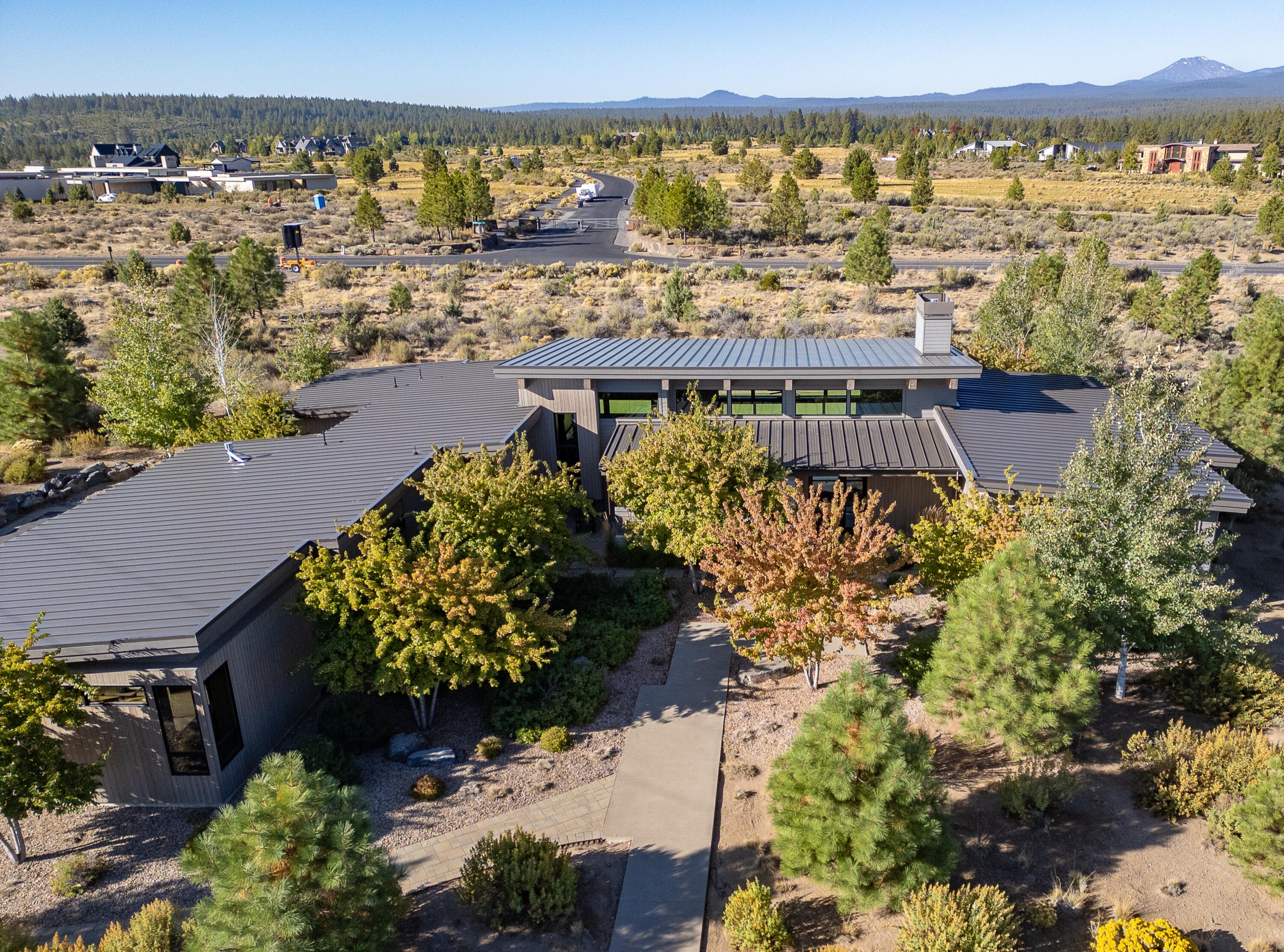 Experience single-level living at its finest in this Tetherow retreat, designed to showcase panoramic Cascade Mountain views. The great room features soaring ceilings, exposed beams, and a wall of sliders that blur the line between indoors and out. Modern statement pieces are balanced with warm wood accents, creating a timeless aesthetic throughout. The flexible floor plan includes three ensuite bedrooms, a private office, and a spacious media room. Outdoor living is at the forefront with a turf yard and oversized patio with outdoor kitchen for gatherings out back and a covered front patio for a quiet morning coffee as well. The primary suite and office/den are privately situated on one end of the home, while two guest suites and the media/bonus room occupy the opposite wing. With golf, trails, and skiing essentially out your door, this home offers a rare combination of luxury, versatility, and connection to the outdoors in one of Bend's most desirable communities.