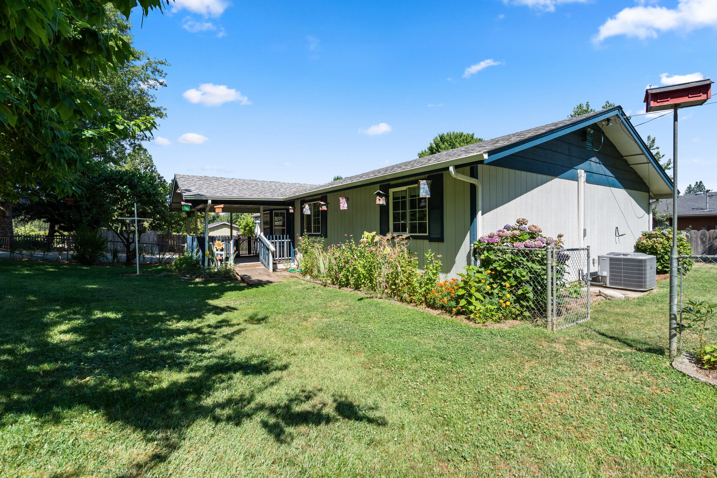 Charming large front deck. Corner lot on a quiet cul-de-sac, just on the edge of town. This house is ready for your personal touch. Recent updates include vinyl windows, newer HVAC system, and new UV light for clean well water. Best of both worlds, well water and city sewer. Yard is fenced and gated with GPID for watering. Well-established fruit trees. Two entrances with two concrete pads for boat or RV parking. 4 bedrooms and 2 full baths, plus two sheds. Workshop set-up in the garage with lots of storage. Laundry room was added inside the garage. Appointment only.