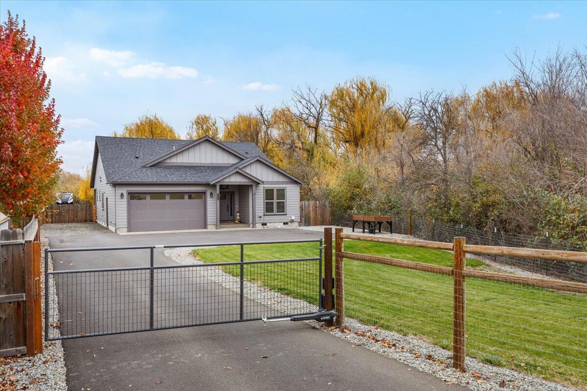 2022 year built 3 bed 2 bath 1772 SQFT custom home on a generous .52AC lot fully fenced,  gated with lots of room for parking, mature landscaping and privacy. There is a adjacent 1.89 AC lot that included in the sale with endless options. Inside the home you will find an open floorplan with the well appointed kitchen as the center of the house complete with custom cabinets, stone countertops, SS appliances and open to the living room with tray ceilings, gas fireplace and laminate flooring throughout. In addition to excellent space for parking there is a nice lawn area and covered patio in the backyard. If you feel like exploring, hop the fence and enjoy your 1.89 acres of wooded property full of life right in town!