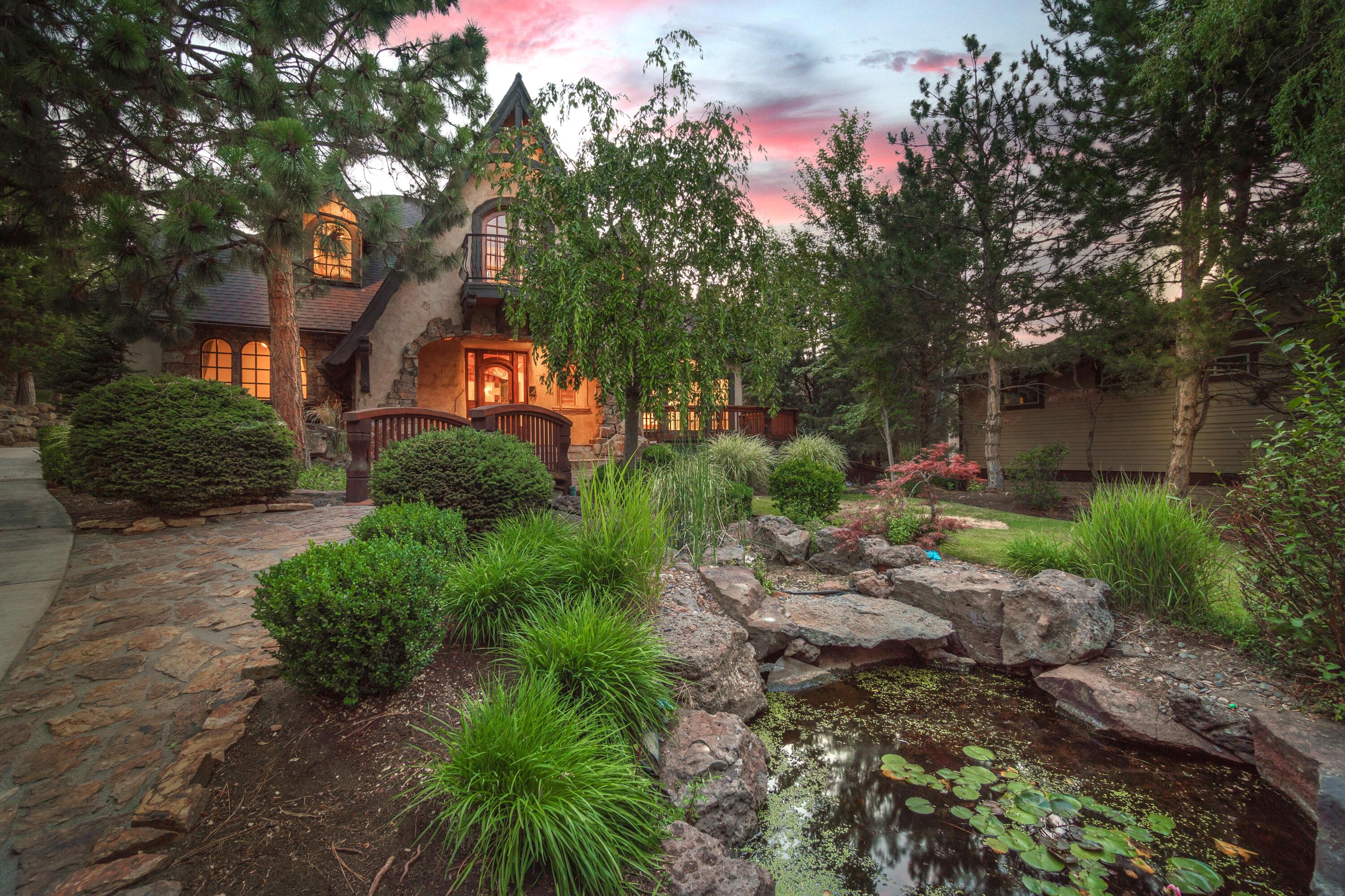 Step into exceptional quality and design in this refined Old World European-inspired haven. Upon entering, you're welcomed through the grand foyer into the vaulted living room with floor to ceiling wood burning fireplace and reclaimed wood flooring and timber beams. The recently remodeled kitchen is a chef's dream, seamlessly blending modern amenities with classic charm. The adjacent breakfast nook opens onto the sunny front patio overlooking the meandering water feature, while the formal dining room leads to the private, rear covered back patio with wood burning fireplace and hot tub. On the main level there's a primary suite and second bedroom, and upstairs includes an office and spacious loft, flanked by two junior suites. The separate mother-in-law apartment above the oversized 3-car garage makes this the perfect multi-generational floor plan. Situated on a lushly landscaped 0.43 acre lot, close to the neighborhood park and river trail. Your dream home awaits!