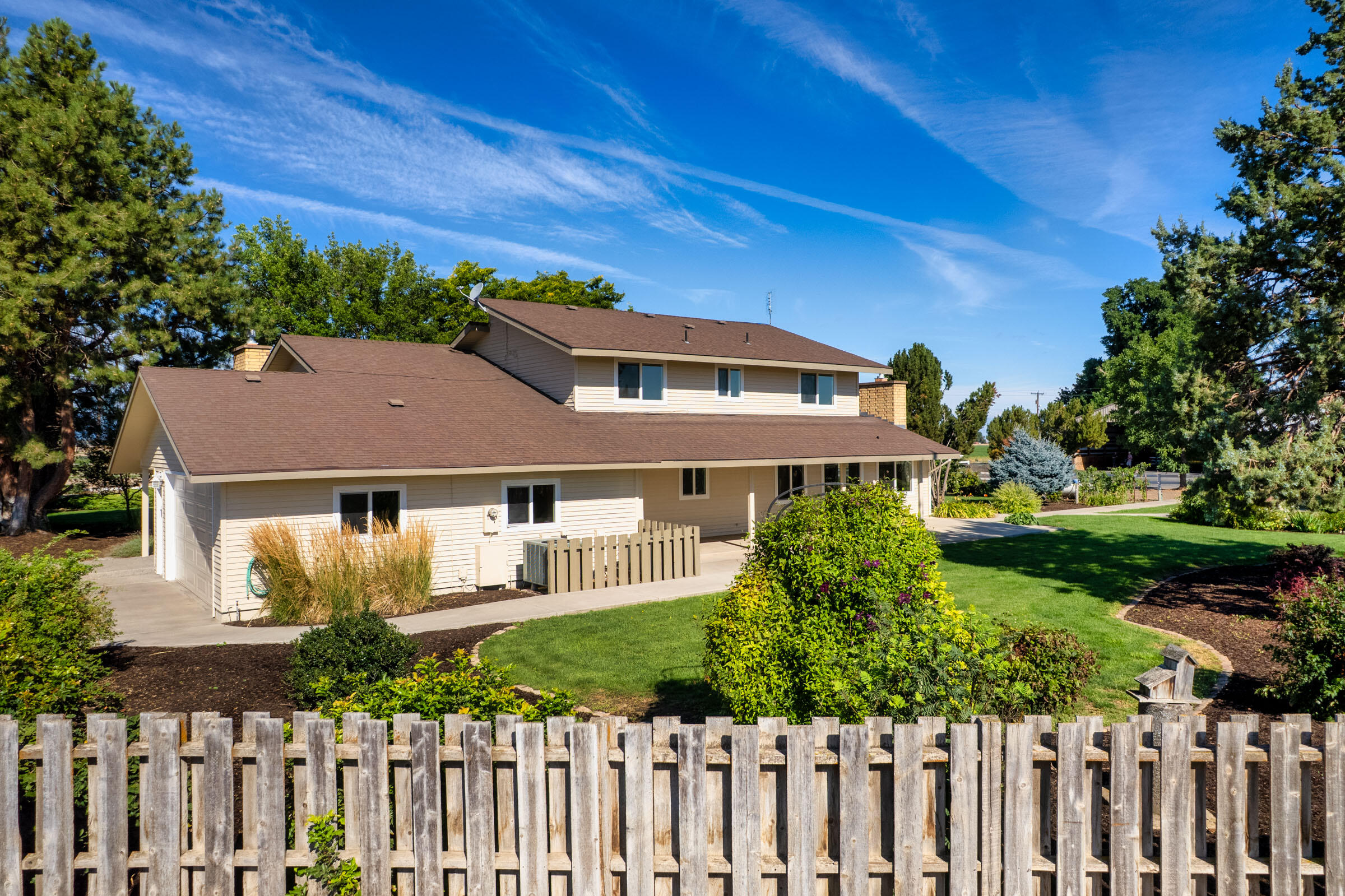 This beautifully maintained two-story home sits on a peaceful 35-acre farm just five minutes from town, offering the perfect balance of comfort, style, and rural charm. Recently painted and thoughtfully updated, the residence features a bright kitchen with modern finishes, a cozy family room, and a private office. Upstairs, the spacious primary suite includes a fireplace, spa-like bath, and serene Cascade Mountain views. Step outside to a landscaped yard with mature trees, a paved patio, soothing water feature, and a fire pit for evenings under the stars. Beyond the home, the property offers 35 acres of productive pivot-irrigated farmland ideal for hay or crops, along with three impressive outbuildings: a 2,668 sq. ft. shop with multiple bays, RV hookups, insulated workshop, and bath; a 2,328 sq. ft. utility building; and a 1,440 sq. ft. hay cover. This property blends modern comfort with country living and plenty of room to work, play, and unwind.