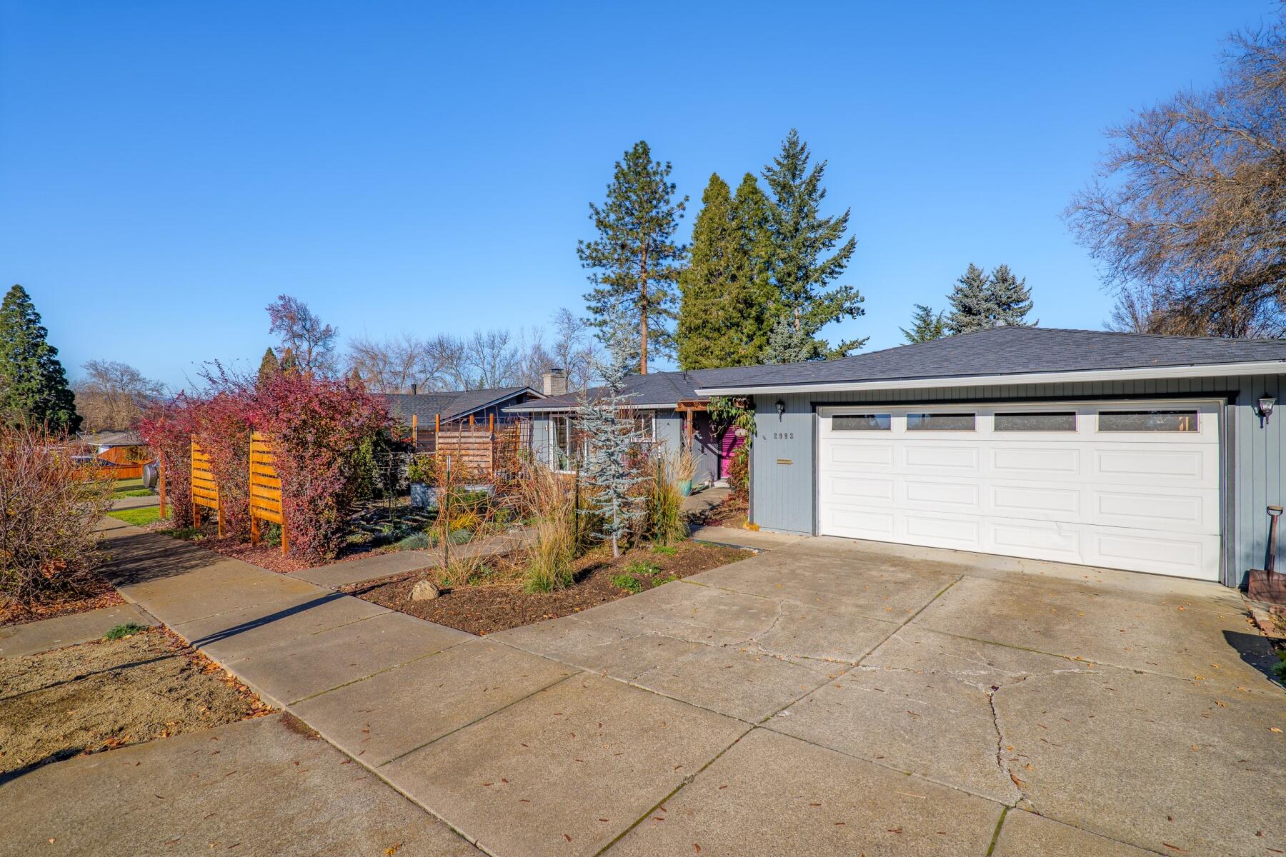 This single level home is in an established East Medford neighborhood near Rogue Regional Medical Center (Asante), doctor's offices, shopping, restaurants, and Rogue Valley Country Club. This is a gardener's dream with extensive plantings, multiple patio areas with three sliding glass doors to the private patios and gardens along with custom front yard fencing.  The interior of the home lives large with 2174 feet, 3 bedrooms, one primary suite with sliding glass door to gardens and a second junior suite, 2 full baths and 2 additional ½ bath, multiple living spaces with a terrific lighting, oversized great room with vaulted ceilings and extensive built-in bookcases, high-end display cabinets and overall endless storage.  New roof in 2022.