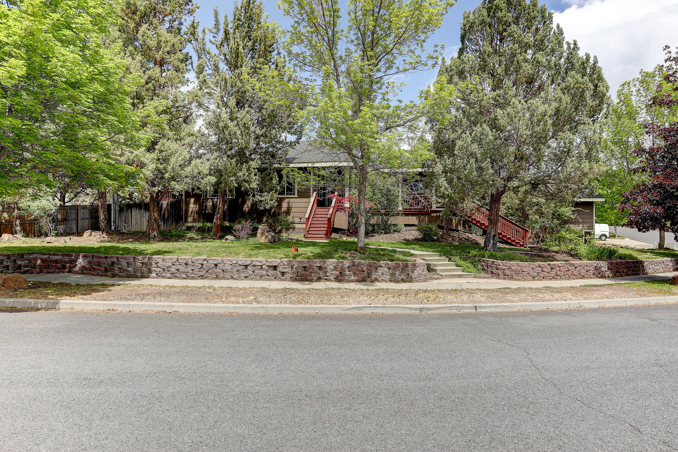 Beautiful 2,182 sq ft single level home on .31 of an acre among mature trees giving you a feeling of privacy and serenity. Huge wrap around deck in front and back with built-in BBQ/refrigerator for all of your entertaining needs. The kitchen features a custom hammered copper range hood over the kitchen island cooktop and granite counters. Great light with large windows and open floorplan showcasing the hickory flooring.  Great separation of space with primary bedroom and office on one side of the home with 3 bedrooms on the other. Gas fireplace in the main living area as well as the primary bedroom. An abundance of storage and parking with a heated 3 car garage . Spacious and fenced back yard is ready for your personal touches plus room for the RV!