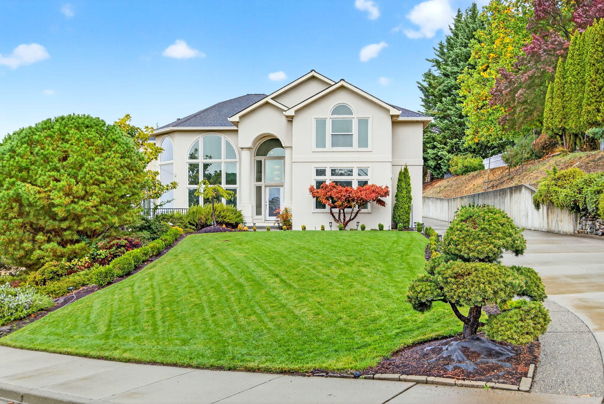 Breathtaking panoramic valley views set the stage for this elegant East Medford home, perfectly situated on a flat, usable half-acre. Thoughtfully designed for both comfort and entertaining, it features soaring ceilings, a dramatic entry with sweeping staircase, and a wall of windows that flood the home with natural light. The spacious kitchen offers an island, walk-in pantry, and butler's pantry with wet bar, while the large dining area is ideal for gatherings. With 4 bedrooms plus an office and a bonus/media room, there's room for everyone. The luxurious primary suite is a true retreat with a spa-like bath and walk-in closet. Outside, enjoy the stunning views from a resort-style pool and spa with cascading waterfall, outdoor kitchen, and beautifully landscaped grounds. A fenced garden area is perfect for growing your own vegetables or creating a private outdoor sanctuary. A detached 3-car garage complements the attached 2-car, providing abundant space for vehicles and storage.