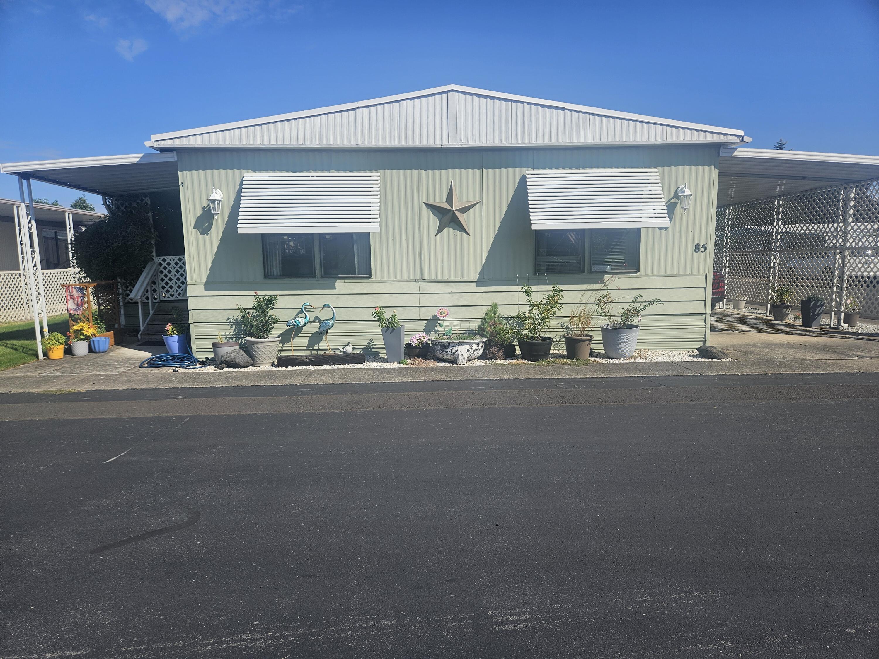 This 1742 sq. ft. manufactured home has 2 large bedrooms and 2 full bathrooms. The master bedroom has its own private bathroom 2 closets. One is a walk in closet. There are 2 family and dining room with a wet bar in between them. Office / utility room. The fenced area has sprinkler system. Private covered front porch and carport. 2 outbuildings, one is a workshop. New belly wrap and vapor barrier installed 2025. New kitchen flooring 2025. There is a community pool, hot tub, pool table, exercise room, and a community kitchen. They have holiday get togethers.