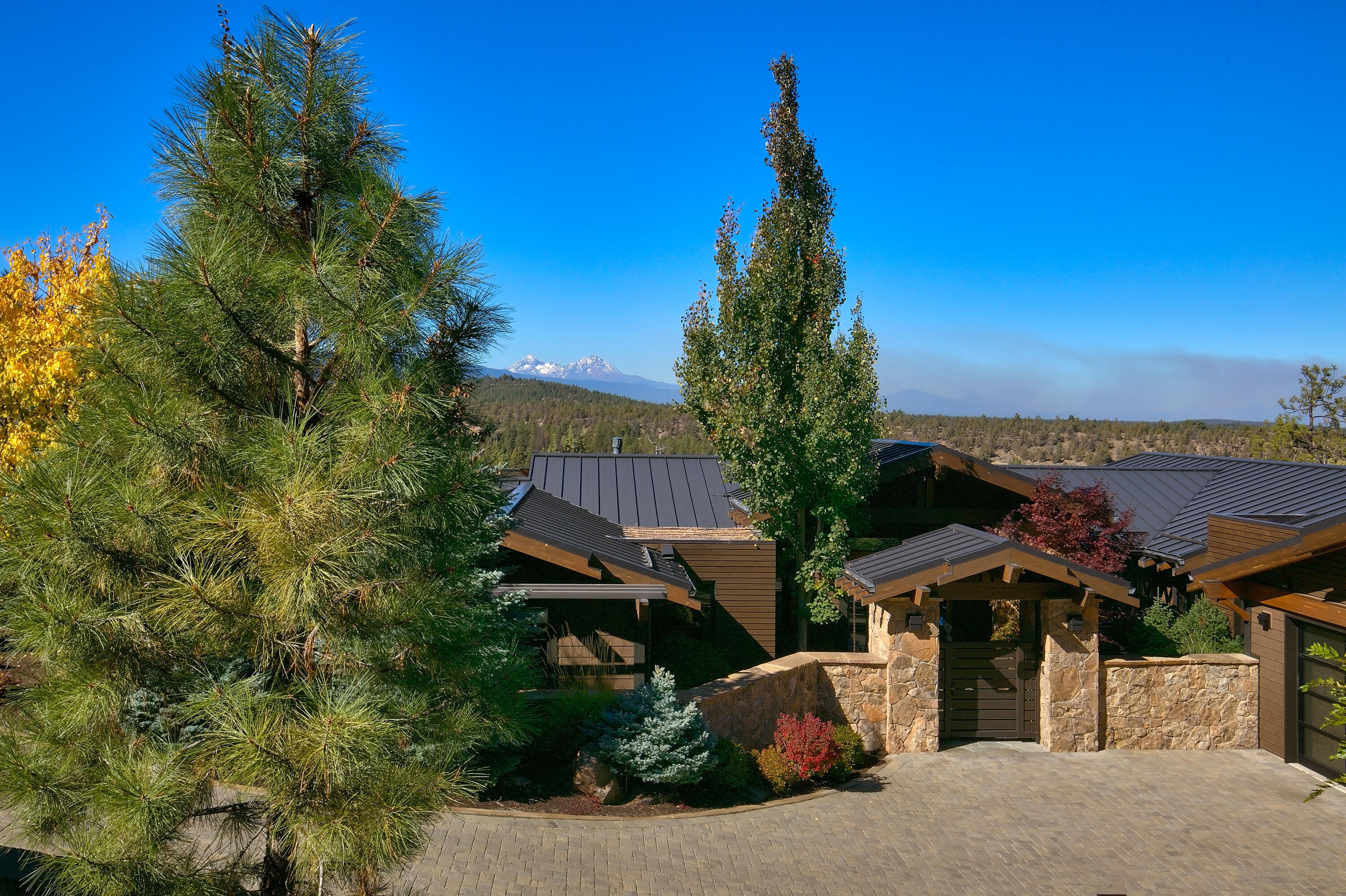 This luxurious custom home is positioned perfectly to capture a stunning view of 10 peaks and ensure maximum privacy. It sits on a premier lot adjacent to the Deschutes River Trail, surrounded by natural beauty in the North Rim community. The interior features soaring ceilings and expansive windows, complemented by rich beams and extensive stonework. The awe-inspiring kitchen is perfect for gatherings and seamlessly connects to an expansive covered deck, immersed in picturesque landscapes. Here, you'll find an impressive outdoor fireplace and seating area for year-round enjoyment. Custom cabinetry and closets are thoughtfully integrated throughout the home. For those with an active lifestyle, a custom-designed exercise pool awaits. In addition, the property boasts a heated driveway, 3-car garage, including an RV bay with an 11 ½-foot door. The residence is equipped with a Control 4 smart home system, ensuring modern convenience and security. This home truly exemplifies luxury.
