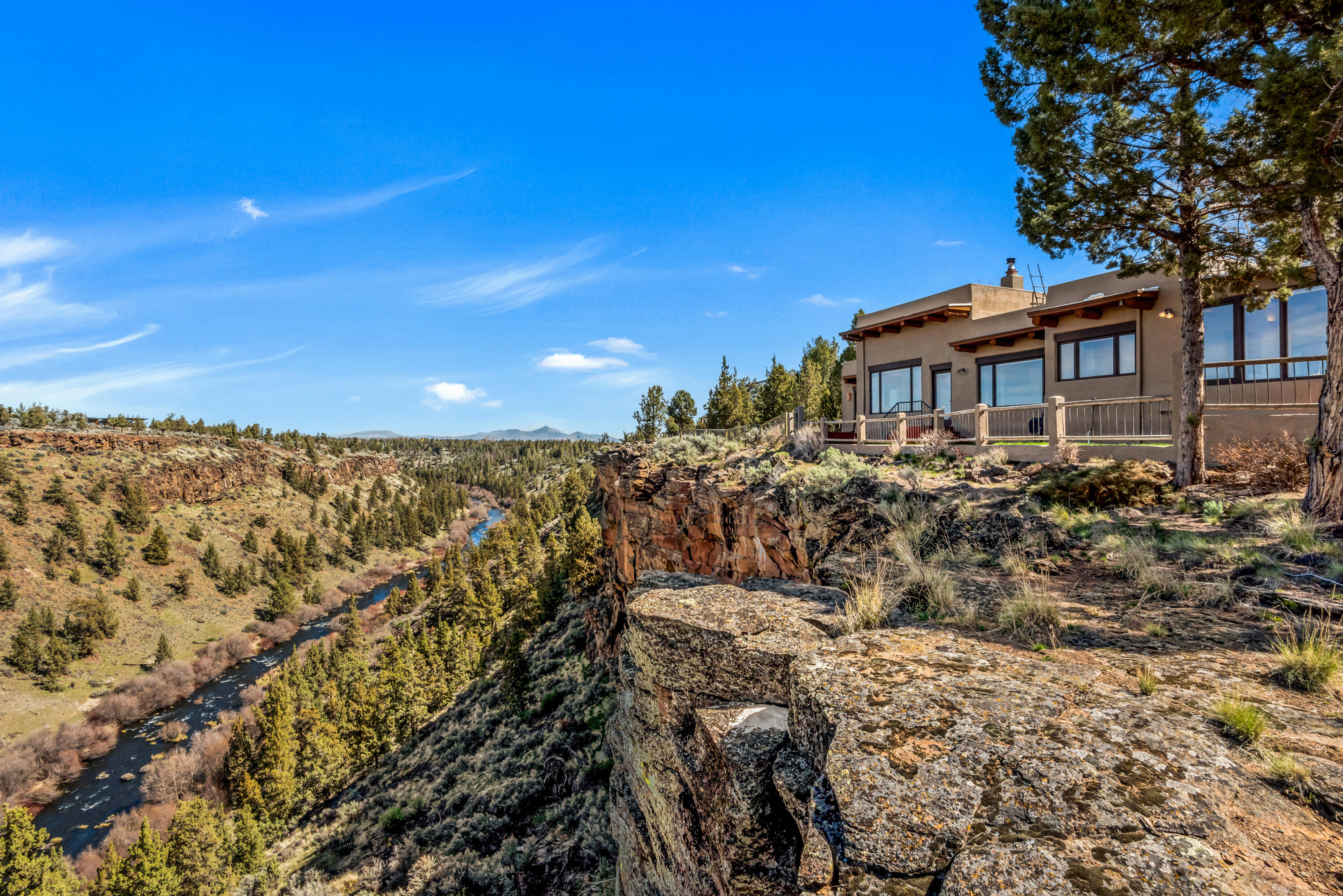 Enjoy breathtaking sunsets and stunning views of a gorgeous river canyon, the Cascade

Mountains and Smith Rock from this Santa Fe style home on a bluff overlooking the Deschutes River. The 2.69 acres extend to the river, across from public land.  Adobe style elements throughout with exposed beams and wood inlay ceilings, a central fireplace, tile floors with radiant heat. Private primary suite with views and separate patio.  Multiple outdoor spaces for enjoying the high desert landscaping and sounds of the river. In addition to a 2-car attached garage, there is a detached shop for hobbies or staging outdoor adventures. This private single-level home has a gated entry, looks out to County and BLM land across the River, with a location convenient to outdoor recreation and the Redmond airport.