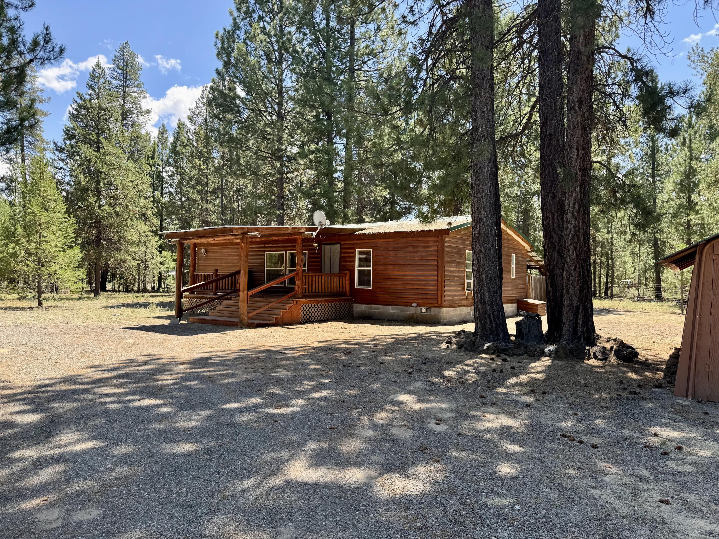This rustic cabin offers an excellent opportunity to enjoy life in the woods. Built in 1995, this manufactured home rests on a generous 1-acre lot and features 1,232 square feet of living space. With 3 bedrooms and 2 bathrooms, the primary bedroom is thoughtfully designed to provide privacy away from the other two bedrooms. 

The kitchen is well-equipped with an island and a skylight, promoting both functionality and natural light. The covered front and back decks create inviting outdoor spaces for relaxation and gatherings. Fenced Backyard. Additionally, the presence of storage buildings ensures that outdoor equipment and belongings are organized and easily accessible. Paved Street to property. This cabin presents a wonderful chance to embrace a serene lifestyle in a beautiful setting.