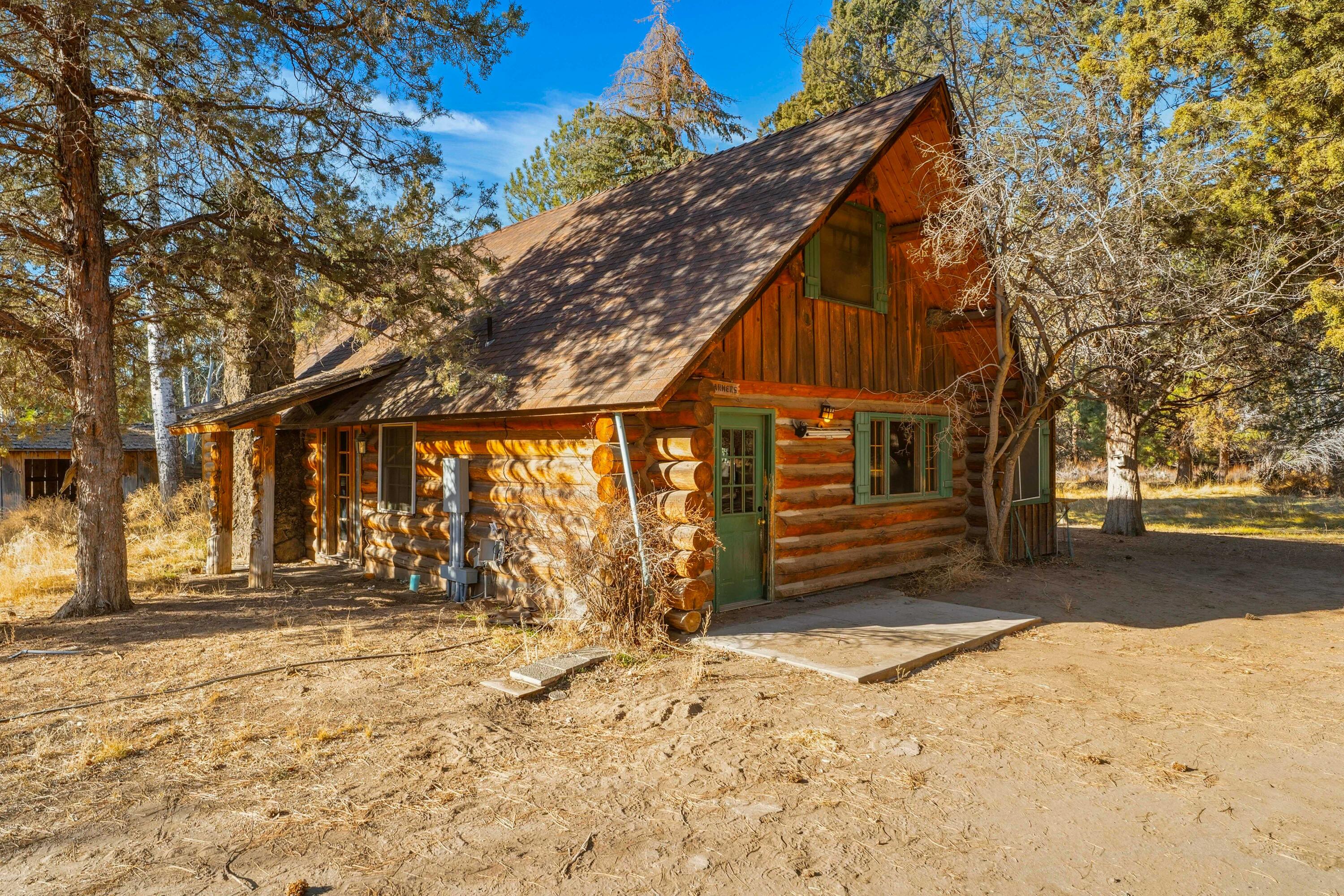 Live the Central Oregon hobby farm lifestyle without giving up convenience. This private log home on nearly 5 irrigated acres offers the rare combination of country living just minutes from Bend. With approximately 4 acres of irrigation, fully fenced paddocks, and room for animals, gardens, or horses, this property is ideal for anyone dreaming of a hobby farm near Bend, Oregon.
The charming 2-bedroom log home features a primary bedroom on the main level, warm wood interiors, and a cozy, rustic feel that blends perfectly with the surrounding landscape. Tucked away for privacy, the property feels worlds apart, yet is just a 5-minute drive to restaurants and coffee shops and only 7 miles to downtown Bend. An additional smaller cabin on the property adds flexibility—perfect for guests, a home office, studio, or more. Whether you're searching for a log home near Bend, irrigated acreage, horse property, or a peaceful retreat close to town, this property checks all the boxes.