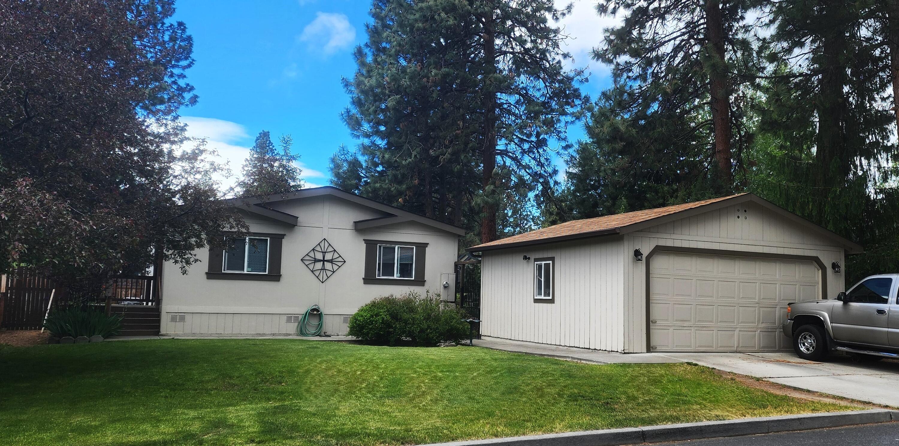 Cute, well-cared for home in Fox Hills family park in Bend.  Efficient, open floor plan with vaulted ceilings and wood laminate floors.  Spacious kitchen with lots of counter space, island with breakfast bar, SS range/refrigerator, and pantry.  Separate laundry room is connected to primary bathroom. Large primary bedroom has good separation from additional two bedrooms. Walk-in shower in primary bathroom. Central A/C.   Enjoy morning coffee on your front or back covered deck. Private, fenced back yard. Detached two car garage. Quiet neighborhood. Space rent is $886.73               and includes water, sewer, clubhouse, and street snow removal.  Home sold AS-IS. Come check out this terrific home!
