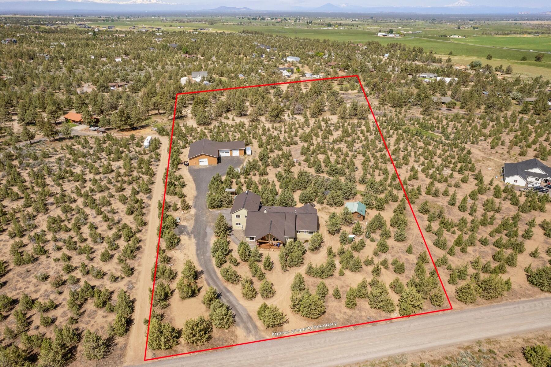 Stunning views with endless opportunities! Nestled on 5.36 acres, this prime property has impressive mountain views (Cascade & Grizzly Mountain), a gorgeous 3,529-sq-ft custom home with 3 bedrooms, 3.5 baths & high- end finishes throughout, plus an attached 3-car garage, R/V parking & hook-up. First-floor features include a dramatic vaulted living room with wood-burning fireplace & a well-stocked kitchen with walk-in pantry. The second story is set up for multi-generational living, with full bath, kitchen, bedroom, living room, gas fireplace & breathtaking views off the balcony. Ideally suited for work projects large & small, the massive 3,660-sq.-ft. shop features 10-foot doors, 12-foot ceilings with vaults & 400 amps of power. There's also a permitted 300-sq-ft log cabin with a full bath, bunk beds & is ready for a wood stove. The backyard oasis is studded with lush trees & has both front and back porches, a fire pit, koi pond, chicken coop & more.
