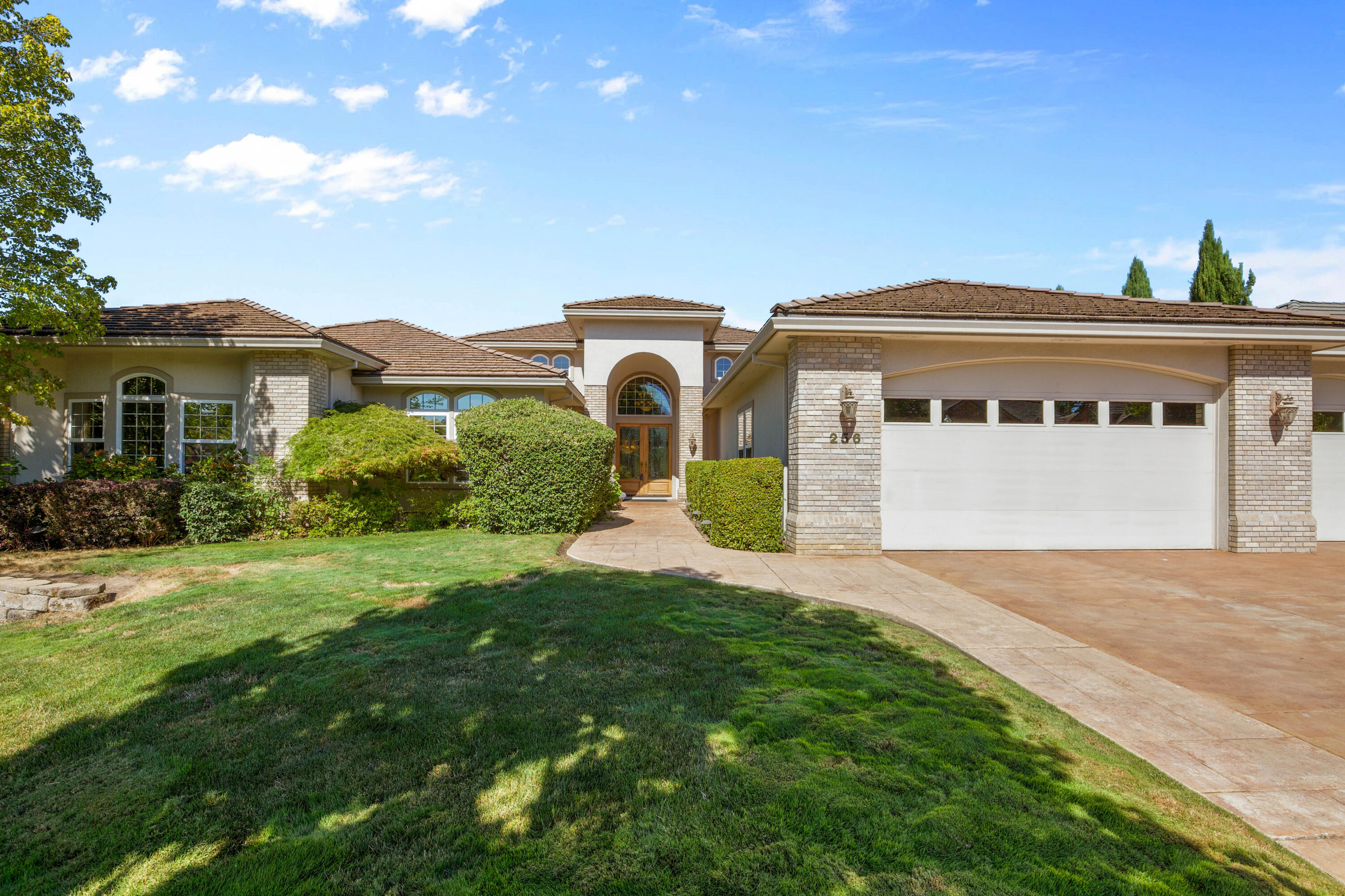Tucked behind the gates of the prestigious Island Pointe community, a one-of-a-kind opportunity awaits—this custom-built masterpiece has had only one owner. Perched on the 12th tee of Rogue Valley Country Club, the 4,118 sqft single-level home was designed for both comfort and grandeur. Step inside to be impressed with soaring ceilings, a dramatic wall of windows, cozy gas fireplace, and built-in TV—an entertainer's dream. The heart of the home, a chef's kitchen, is equipped with granite counters, double ovens, a warming drawer, and thoughtful pull-out cabinetry. The luxurious main suite offers a spa-like escape with jetted tub, walk-in tile shower, dual vanities, and a grand closet. A second primary suite on the opposite wing creates ideal flexibility for multigenerational living. With 5 bedrooms, 4 bathrooms (3 with heated floors), a 4-car garage, remote patio awning, and more, this exquisite home offers luxury living with breathtaking golf course view.