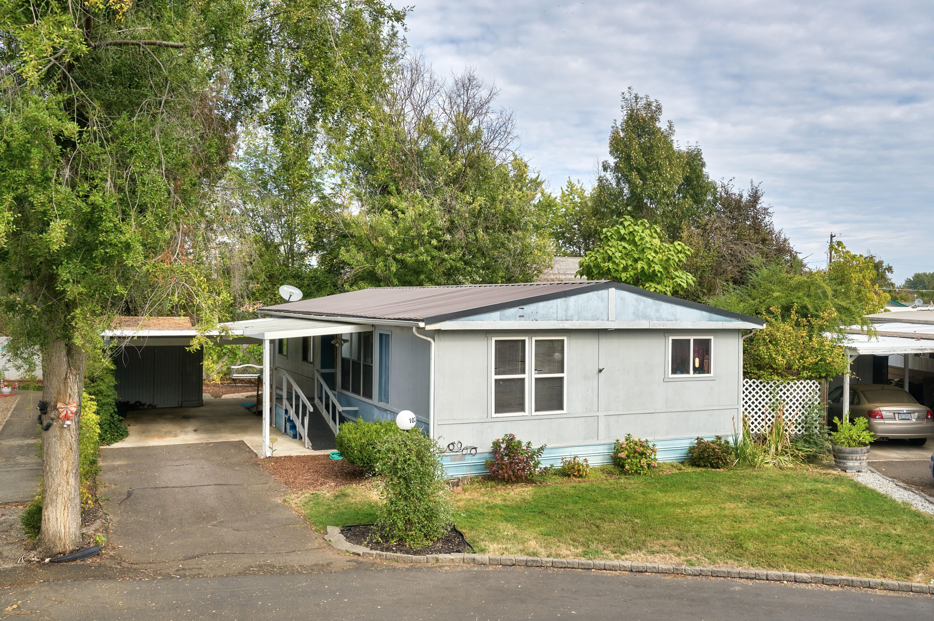 Great home in the Rogue Valley Meadows 55+ community. This 2 bedroom 2 bathroom home is 1152 sq ft and is located in a cul-de-sac. The home has a very large, carpeted living room area. The kitchen has an eating bar and includes the refrigerator, range and dishwasher. It has updated laminate flooring in both the kitchen and dining area where there is a nice built-in cabinet. One of the rooms is extra-large and has built in dresser drawers. Outside there is a covered deck that overlooks the low maintenance side area with walk path that wraps around the home. The home incudes 2 outside storage/sheds. Large carport and wheelchair accessible ramp. The Rogue Valley Meadows community has access to the club house and workout equipment.