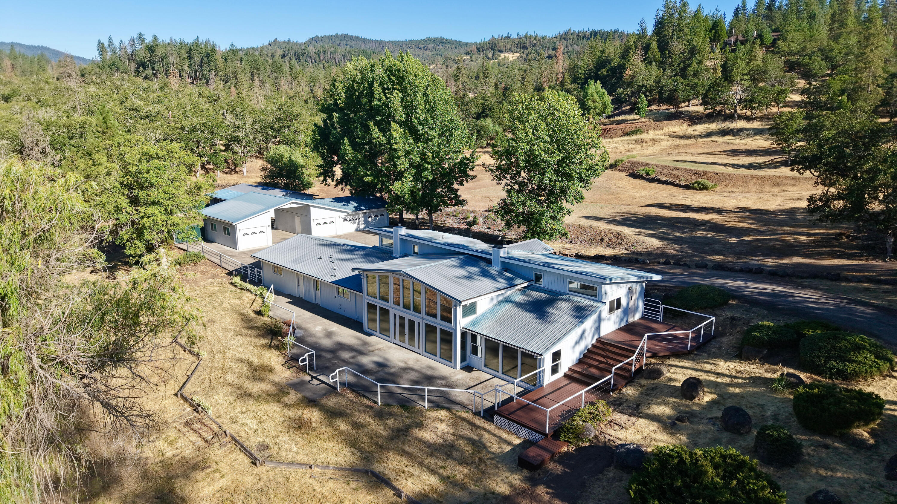 Country living on 12+ acres. This 3,102 sq. ft. multi-level home sits on 12.18-acres & offers 3-bedrooms & 3-bathrooms with plenty of space & potential for updates. Built in 1992 on a concrete block foundation, the home features a large flex space entry that leads into the kitchen, dining area & living room. The kitchen and dining area both have tile flooring, and the dining space is highlighted by a wall of windows inviting in natural light and a staircase leading to the upper-level bedrooms. The living room, open to the kitchen & dining area, features a cozy gas fireplace. A separate main entry also provides access to all bedrooms and bathrooms, including a primary suite with its own gas fireplace and a jetted tub in the bathroom. The property includes a metal roof, animal stalls, pasture, a detached 4-bay garage with 30-ft RV parking in the center, a shared well with a strong flow history & septic system. It needs some TLC but has solid bones and great potential.