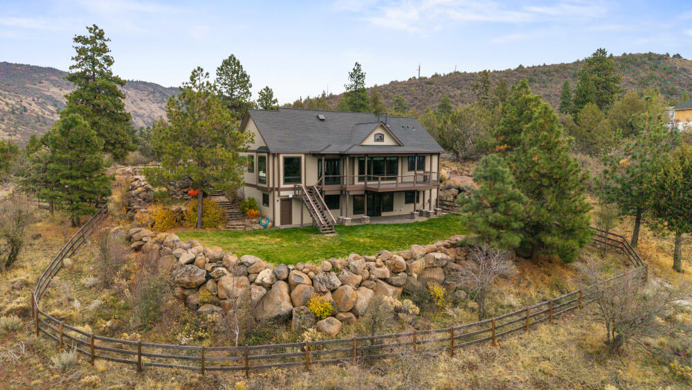 Luxury home on 5 acres w/panoramic views. This 4bed/3bath home in a gated community blends thoughtful elegance & efficiency with solar power & a backup Generac generator. The dramatic entry opens to the great room with hand-scaped wood floors, vaulted ceilings & picture windows. The open floor plan flows out to the Trex deck or into the dining area, then to the gourmet kitchen with stone countertops, high-end appliances & a breakfast nook surrounded by windows framing the mountain & lake views. The primary suite on the main floor offers his & hers walk-in closets & en suite bathroom w/ jetted tub & custom-tiled shower. Downstairs features a family rm opening to a patio w/built-in gas line for BBQ plus a bed, bath, office w/storage & bonus work rm w/backyard access. Off the utility rm the 3-bay garage includes a custom dog kennel system & ample storage for work and play. Beautiful and low-maintenance landscaping, fully fenced yard, RV parking w/possible hookups—this property has it all
