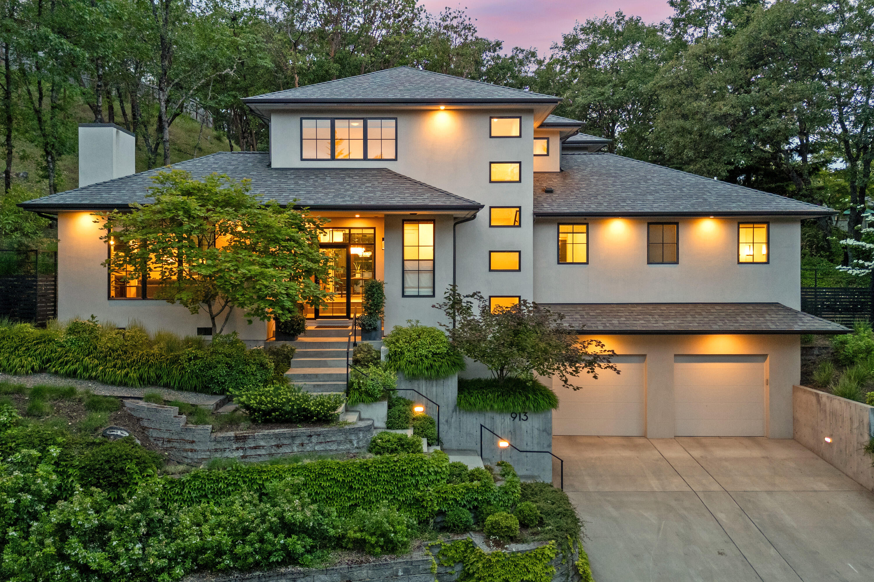Timeless contemporary style and design. This stunning home is nestled into the hills above the boulevard in beautiful Ashland Oregon. 4 bedrooms, 3 1/2 baths w/approx. 3081 SF. Warm and inviting home w/ lots of natural light pouring in from the many windows, also capturing the picturesque treed setting that surrounds. Main level is up from the garage, perched above the street providing a nice sense of privacy. Light filled entry leads to a cozy living room w/ gas fireplace and spacious dining room w/ access to the lovely terraced backyard patio perfect for entertaining. White Oak engineered floors, tall 9 ft ceilings and 8 ft doors. Chef's kitchen w/Thermador appliances, quartz countertops, large center island and lots of cabinetry for storage. Primary bedroom suite w/ dual vanities, large shower and walk-in closet. Remaining bedrooms are upstairs, one en-suite and the other two share a full bath. This is an impressive property with a great location, close to a vast network of trails.
