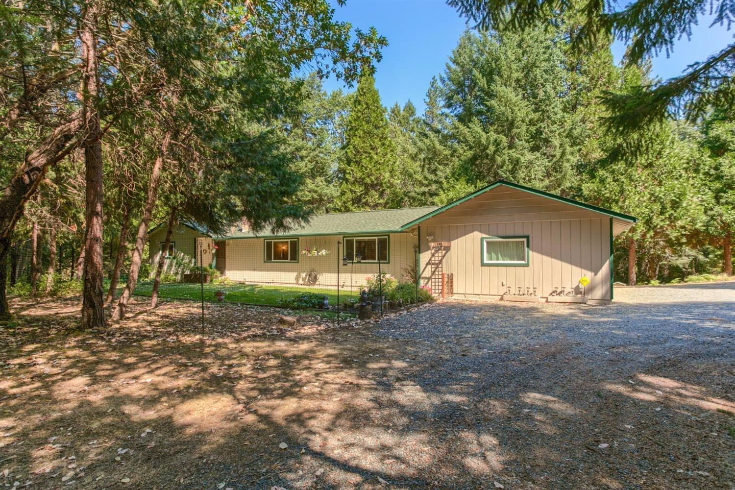 Private 5+ level acre parcel with delightful single level home with oversized attached garage, plus 960 sf detached shop with 220V power and 1400+ sf of covered RV or equipment storage. Further complimented with the sights and sounds of 600 feet of year round creekfront along one border. Beautiful deer fenced raise bed garden. Newer roof. Updated kitchen with chiseled edge granite slab counters, newer stainless steel appliances, pull outs and generous walk-in pantry. Expanded living on the wonderful covered deck. Huge family room big enough for pool table and the big screen TV. Living room with tile entry and brick hearth fireplace with newer insert. Laundry room with mud sink and raised pedestal washer & dryer. Crown molding throughout most of home. Security gated property is a wooded oasis less than 15 minutes to town.