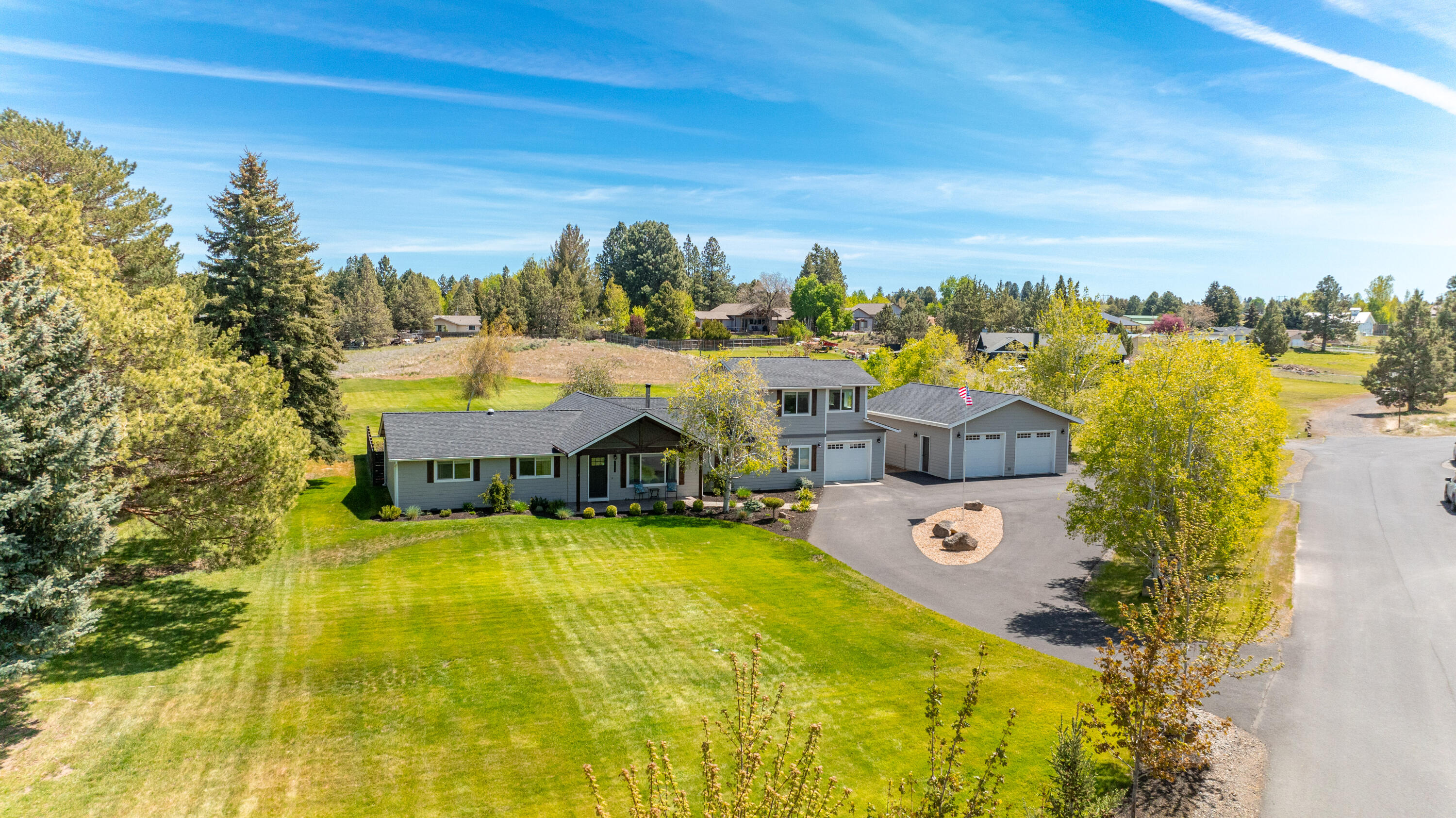 At the eastern edge of town, a little slice of paradise waits for you on nearly two acres, with plenty of room for your shoulders to drop & your smile to grow. Remodeled & expanded, this immaculate home welcomes you into an open main living space where large windows bring in the sunshine. A well-appointed kitchen speaks to your inner chef with a center island handcrafted from reclaimed barn wood & custom metal work. Set apart in its own wing, the primary suite includes vaulted ceilings & a luxurious bath with separate vanities, soaking tub, heated floor & walk-in tile shower. A 2nd primary suite with heated bathroom floors, additional bedroom, full bathroom & office with wood accent wall complete the main level. Upstairs, a large bonus room provides added flexibility. Outdoor living is easy here where a sheltered courtyard includes a paver patio & hot tub & a large pond is surrounded by an expansive lawn. The 1 car attached & 2 car detached garages complete this one-of-a-kind package