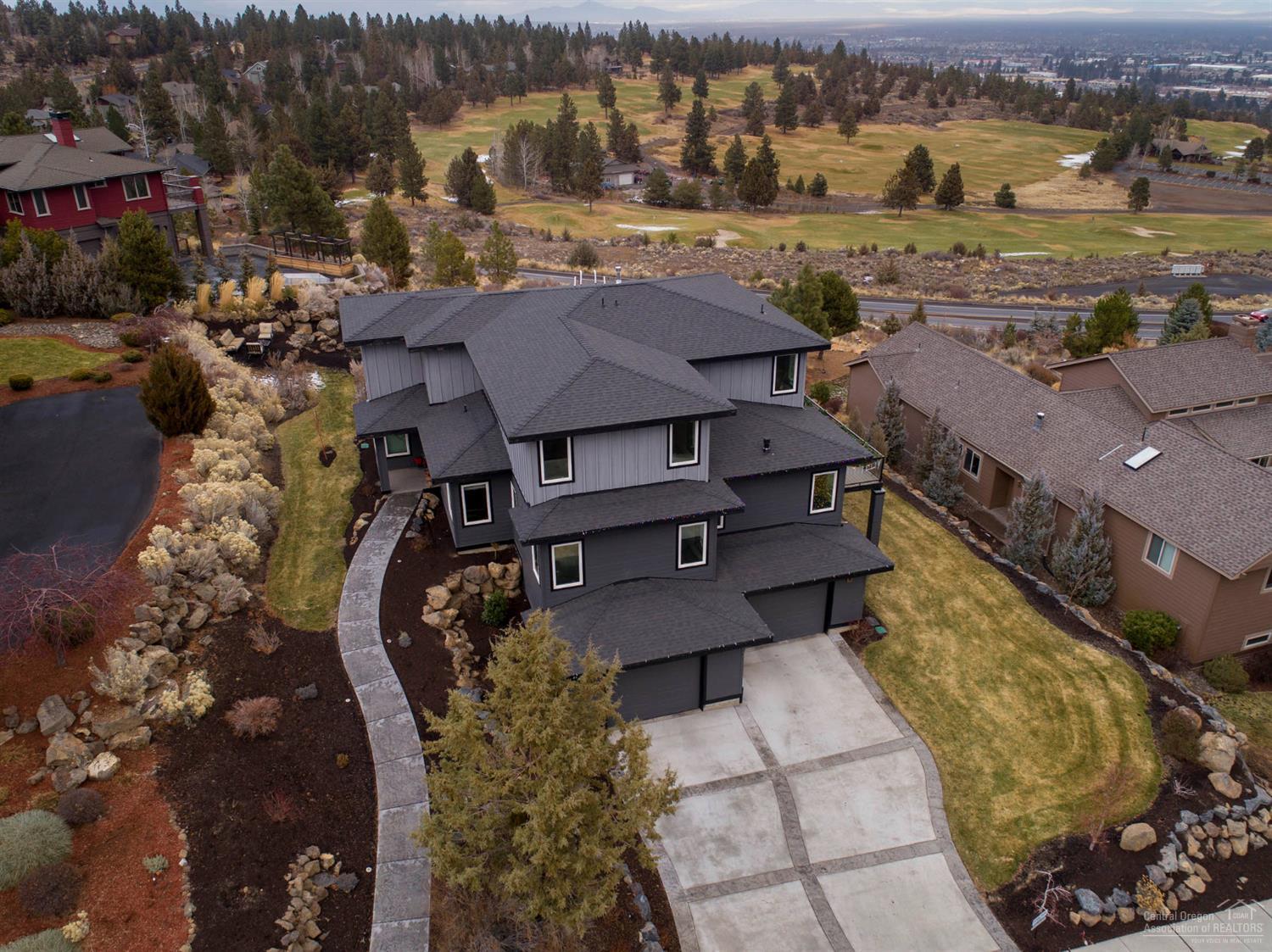 Modern industrial prairie style home w/stunning views of the golf course, city & beyond. Watch the sunrise over the Ochocos & the twinkling lights of Bend every evening. Grand entry leads to Gourmet Kitchen w/bar seating for a small crowd. Open to Living area w/cozy gas fireplace accented w/hammered steel. Recycled brick wall serves as a unique backdrop! Main level Master Suite, spacious Bath w/huge walk in shower & oversized closet. Additional bedroom/office on main floor. Upstairs you'll find 2 guest rooms, deluxe bathroom & a bonus room w/an amazing view from every angle. Sleek staircase wraps around a 3 story tall one of a kind lighting showpiece. 1924 sf Garage w/built in storage, custom floor, dumb waiter & even a wine cellar! Outdoor entertaining areas expand from the wrap around deck to fire pit area that looks over the golf course. Don't miss!