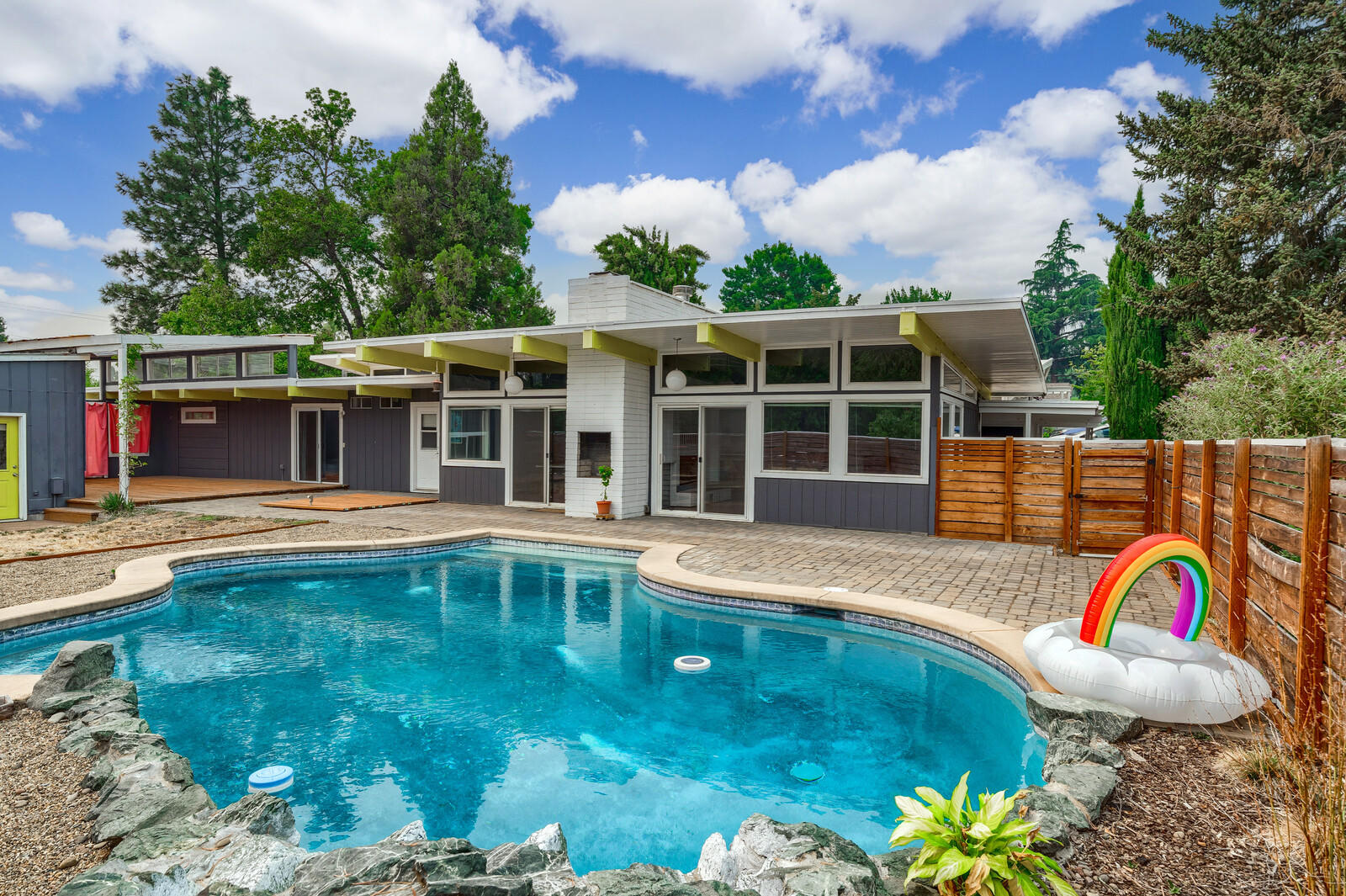 Don't miss this one-of-a-kind Mid-Century Modern oasis in a quiet SE Medford neighborhood. Experience the best of high-style indoor and outdoor living.

This large single-level home has vaulted ceilings and exposed beams. A spacious open kitchen/dining/living area with architectural double-sided gas fireplace has amazing natural light. The living and dining rooms open onto a gorgeous in-ground pool. Several green and smart updates included.

The outdoor living space includes a large deck and patio with pool, bocce court, fireplace, and hot tub-ready platform. A detached 2-car garage with shop space is great for your projects. The property includes plenty of off-street parking and an RV space. The 4th and 5th bedrooms at the back of the house have a separate entrance. There are productive fruit and nut trees, pollinator-friendly landscaping and large raised garden beds.
