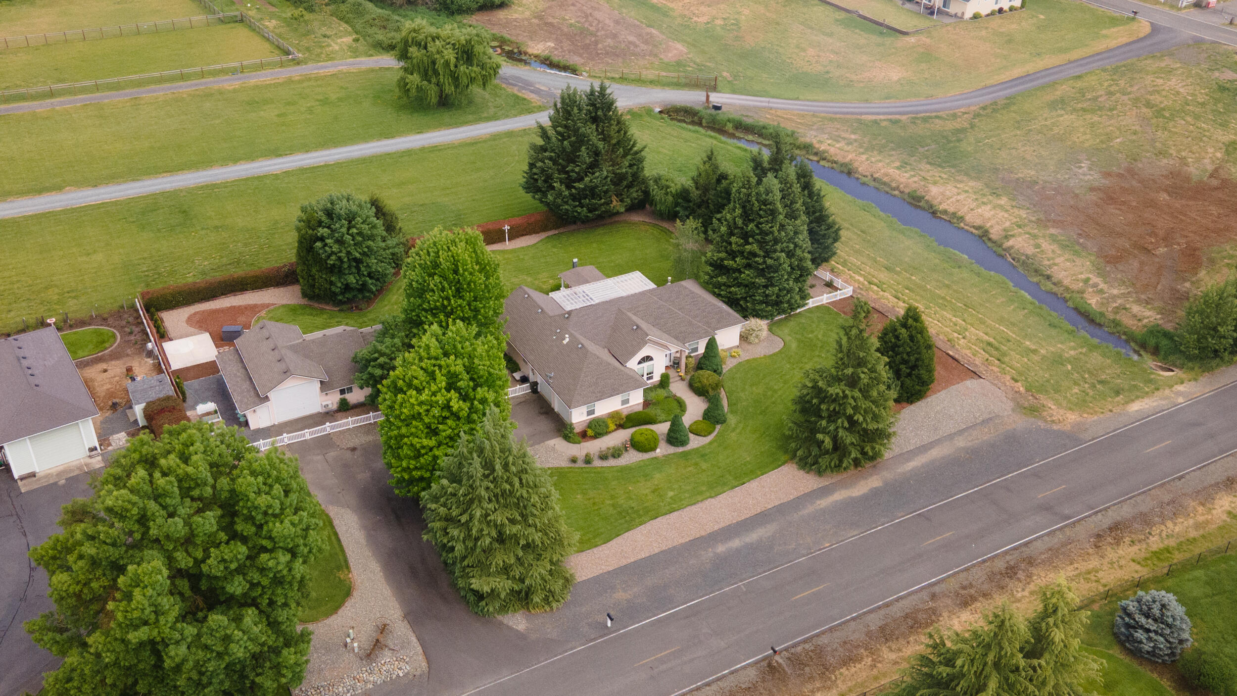 Location! Location! Southern Oregon Dream Property minutes away from the Rogue River and historic downtown Grants Pass. This updated single level home is situated in a peaceful neighborhood on one professionally landscaped acre of land. Features include: split floor plan, maplewood flooring, open floor plan, formal dining, eat in kitchen, and a spacious master suite. Step outside to an additional detached dwelling unit with an RV garage, shop, and locked storage areas that are all ADA accessible. The expansive yard, garden, large covered patio, outdoor covered kitchen with plumbed gas, fireplace, and multiple areas for seating make this home the place for all your family and friends to enjoy! This home has many more amenities. Make an appointment today for your forever home.