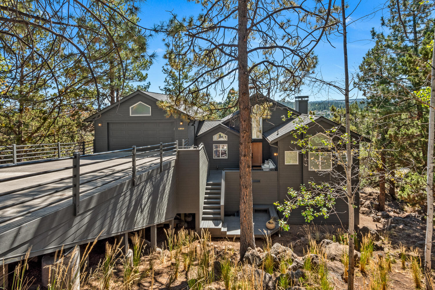 Nestled in the desirable West Hills, this impeccably remodeled home perfectly balances modern sophistication and thoughtful design. Enter into an open-concept great room with high ceilings and expansive windows showcasing stunning views of Mt. Bachelor and the iconic smokestacks of the Old Mill. Relax in the spacious living area featuring a sleek linear fireplace, oak mantle & built-in storage. The main-level primary suite offers a peaceful retreat with a large walk-in closet & custom built-ins. The luxurious en-suite bath includes a deep soaking tub, a spacious shower & dual vanity. Downstairs, find three charming bedrooms, a large bathroom, a versatile bonus room, and 350+ sq ft of bonus room storage. The chef's kitchen is a dream with modern appliances, custom cabinetry & a walk-in pantry. Step onto the newly engineered deck with a hot tub or gather around the terraced fire pit below for outdoor relaxation. Every detail in this home is crafted for comfort, style & functionality.