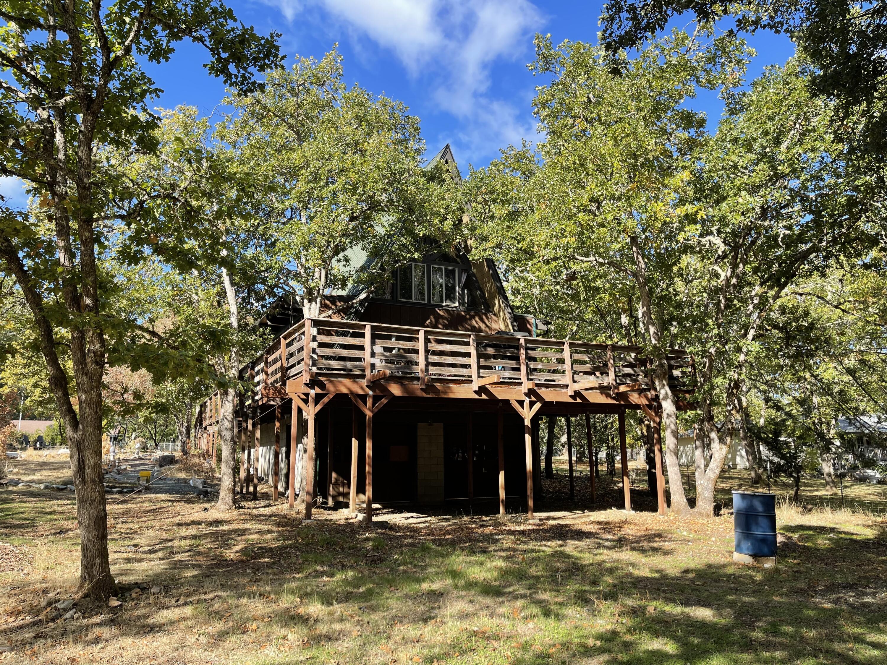Charming cabin amongst an oak grove.  Being sold ''As Is'', updating and finishing touches needed.  Here's this unique A Frame styled home on a nice level one acre lot.  Many upgrades but there's still some finishes that need to be done.  Living  room has soaring vaulted ceilings with open beams that have been recently stained and painted.  Pellet stove with cultured river rock hearth, Kitchen has painted cabinets and eating bar.  Newer engineered wood flooring, bedroom on both floors, hall bath has tile, lots of natural wood siding, sliders and large picture windows, sitting area in loft, 2 car garage under house with washer dryer hook up with sink. Heat pump is newer.  Deck needs work as well, please be cautious and only one person at a time on front deck. CASH or Conventional with a large down payment.
