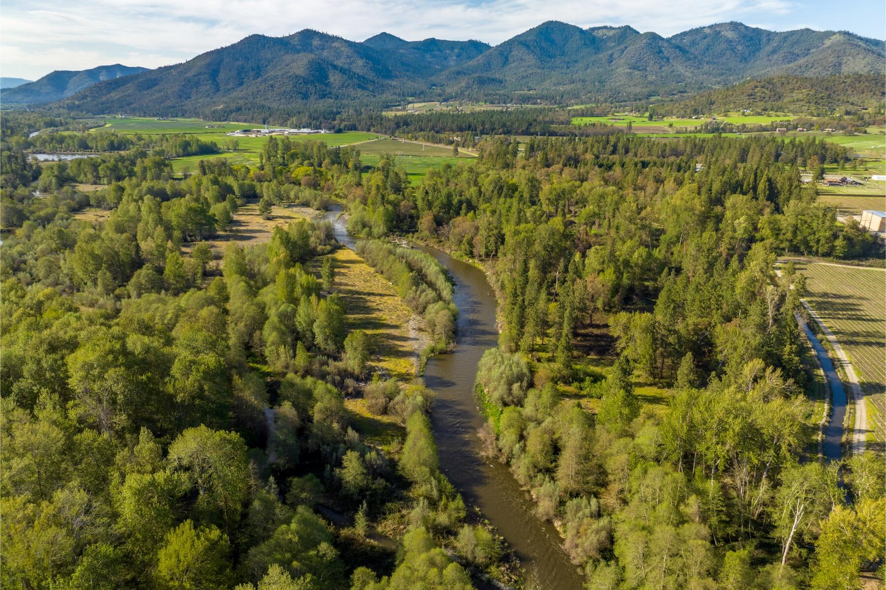 Welcome to 13481 N Applegate Road - A prime riverfront estate in the heart of the Applegate Valley. Available for the first time since 1988. Set on 65.5 acres with over ½ mile of river frontage on the picturesque Applegate River. Providing an abundance of opportunity, this private river retreat lends itself to fishing, waterfowl, upland bird, black bear and blacktail deer along this well-known steelhead fishery. Sitting off the main road, enjoy the quiet and country feel of the exceptionally maintained log home built in 1948. This 1486 sq. ft log home has a lovely character with all the security of a metal roof.  Additionally, there is plenty of room surrounding the home with about 10 acres of flat area perched above the riverbed, along with the classic shop, bunk house and barn. The irrigation maintains the park like setting of mature oaks and conifers. This land has loads of potential, the existing home has endless possibilities.