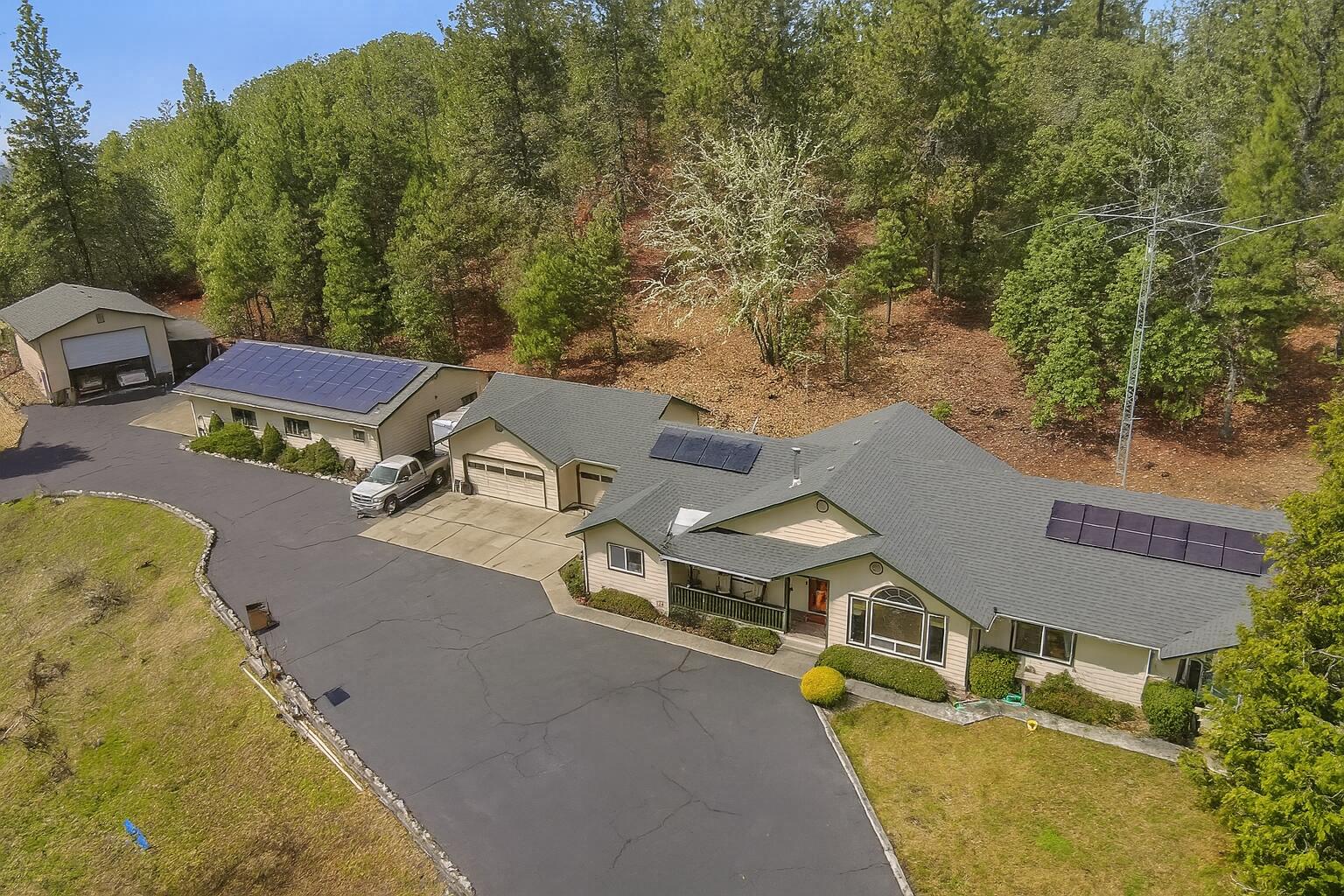 Radiantly Rustic One-Level Home with Solar Panels, Huge Lot, and Multiple Garages! Nestled on a private 5.4-acre lot just moments from I-5, this 3BR/2.5BA, 2,456sqft property offers an unparalleled lifestyle of both leisure and practicality. Explore the residence to discover gorgeous hardwood flooring, vaulted wood beam ceilings, elegant formal dining room, and a spacious living room with a wood-burning stove. Enjoy the modern touches of the kitchen, which delights with stainless-steel appliances, granite counters, wood cabinets, and an island. Relish in the comfort of the primary bedroom, which has an en suite boasting dual sinks, jetted tub, bidet, and a separate shower. Hobbyists and car collectors are sure to bask in the attached three-car garage, secondary garage, and a workshop/garage with an oversized rolltop garage door. Other features: laundry area, covered patio, concrete patio, 11-miles to Downtown Grants Pass, and much more! Start living your best life today.