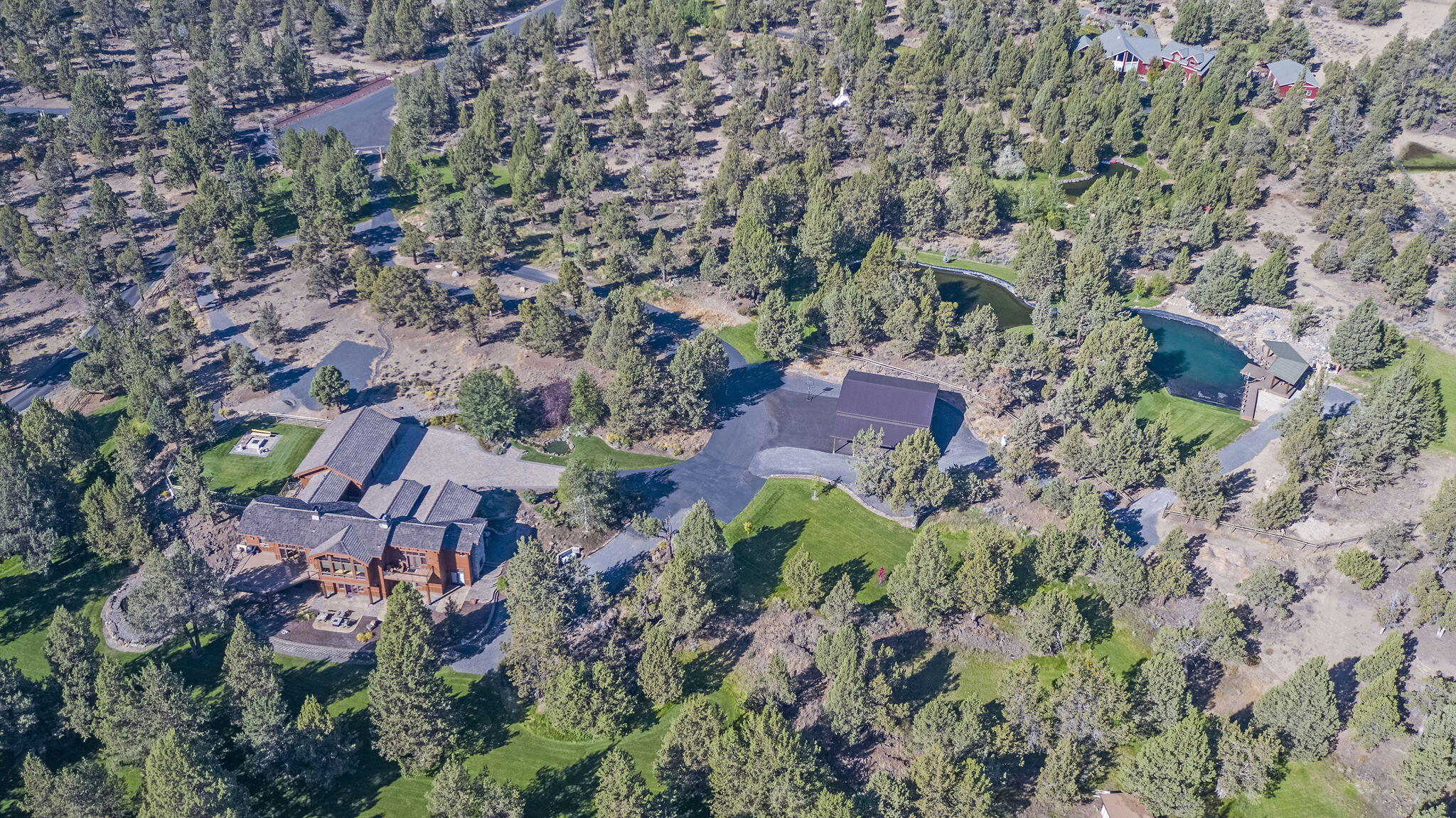 Northwest Luxury Lodge living just 15 minutes from Bend.  From the moment you enter the long-paved drive the attention to detail is evident.  This property boasts almost 10 manicured acres with trails, 800,000 gallon pond and swimming area with custom waterfalls, pavilion and decking, multiple waterfalls throughout the property, fenced dog park with firepit, 1300 sf RV garage, 480 car port, room for everything, the home has 5 full suites, floor to ceiling rock fireplace and massive windows to enjoy the land, chefs kitchen with two islands, media room with full kitchen, downstairs family room, office and ability to create two living spaces.  RV hookups, 3 car garage and more.