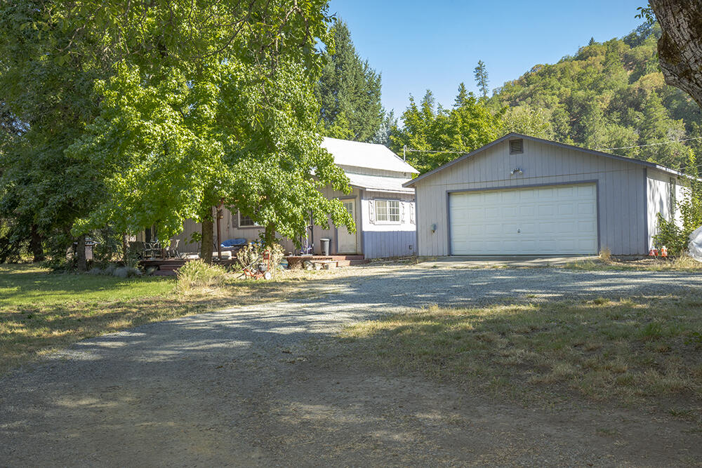 Charming 1910 Farmhouse on Nearly 10 EFU Acres with Irrigation and Views! Welcome to this Applegate Valley homestead, set on 9.42 flat, fully fenced, and usable acres with irrigation rights from Murphy Ditch. This classic 3-bdrm, 2-bth farmhouse offers 1,632 sq ft of cozy living space, featuring a propane stove in the living room, a bright kitchen and dining area, and covered front porch with screened back porch for year-round enjoyment. The property showcases a beautiful pasture with a variety of mature trees, including magnolia, black walnut, cedar, redwood, cottonwood, and hazelnut. A service gate allows for easy RV access, and there is ample space for equipment and animals. Outbuildings include a detached 2-car garage and a 2020-built, insulated, climate-controlled shop with 220 power. Permitted greenhouses and irrigation infrastructure make this property ideal for horses, farming, or homesteading. Located next to the Applegate Golf Course and just minutes from town. Come tour!