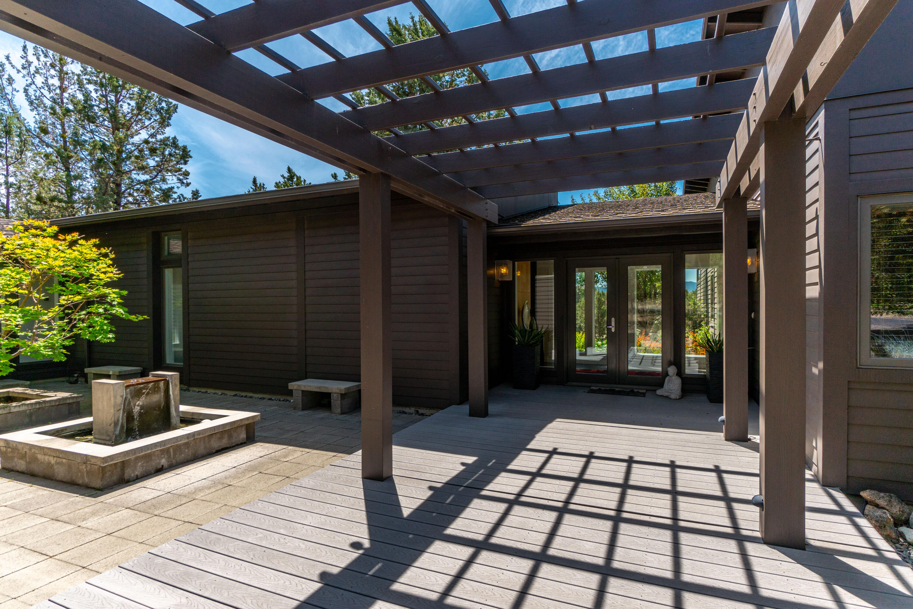 Anchored in classic design principles with a nod to Mid-century architecture, this timeless gem is a retreat in the community of Tumalo. Situated on 5 private acres, this home offers a peaceful escape from the everyday rush but is just minutes from the amenities of Bend. Inside, expansive floor to ceiling windows bathe the great room in natural light, overlooking open land & Cascade mountains. The open concept living area is spacious and flows seamlessly to the outdoors. Take your pick of an expansive west facing deck or a tranquil interior courtyard with mature maples and water feature. The distinctive primary suite includes a gas fireplace, access to the deck & hot tub and abundant custom storage. Two guest bedrooms & separate office/flex space complete the single level floor plan. Custom maple cabinetry is featured throughout the home offering abundant storage in style. Additional perks include an oversized 3 car garage, covered RV parking & charming fenced garden with greenhouse.