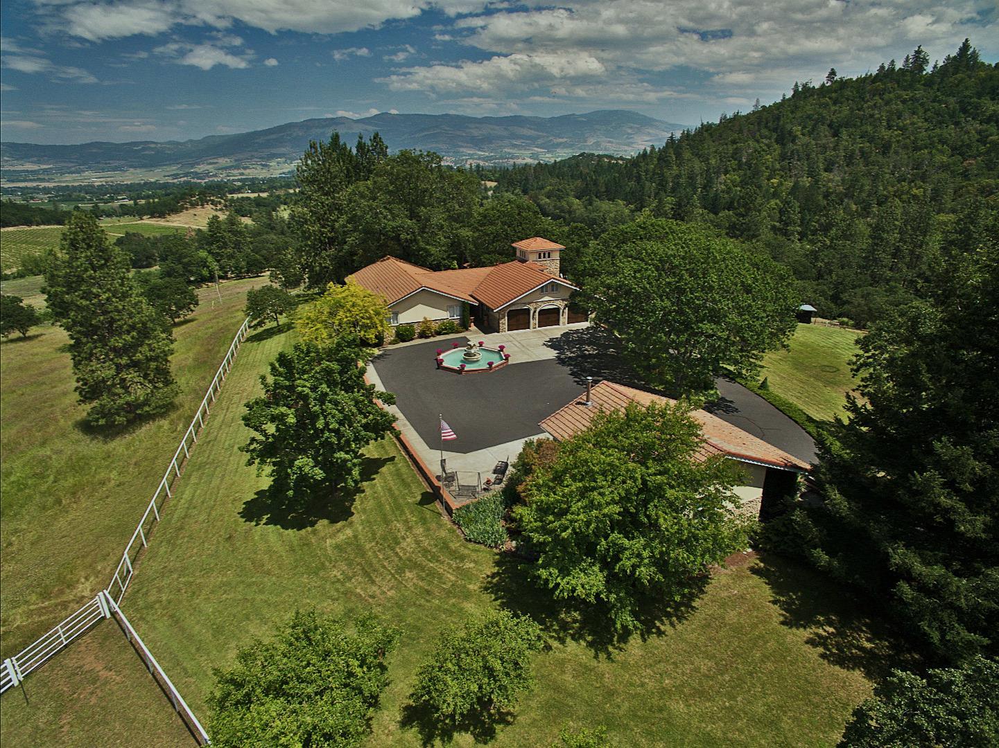 Truly extraordinary properties are different at every level. This, one of a kind Southwestern Equestrian estate overlooks vineyards, pastures, pond and the Cascade mountains. The centerpiece of the property is a 37,100 SF lighted Roping Arena with custom Preifer panels, steer return alley, remote control chute with elevated stripping chute plus holding corral. The main estate boasts indoor/outdoor gourmet kitchens, 4 bedrooms, 4 baths, billiard room with wet bar and exercise gym. Spacious wraparound deck and patio of terracotta concrete with gazebo, fireplace, hot tub spa and outdoor shower. Upper shop is 672 SF with epoxy flooring. Machine shed has 5 bays and attached 2-car garage. 50 X 50 outbuilding has a spacious office, kitchen, bath, artist's studio, security system and double motor-coach capable garage. Barn has 4 box stalls with turnout corrals. Just minutes from Ashland, Jacksonville, shopping, hospitals and airport, this home has it all! Let your dream come true! Carpe Diem!
