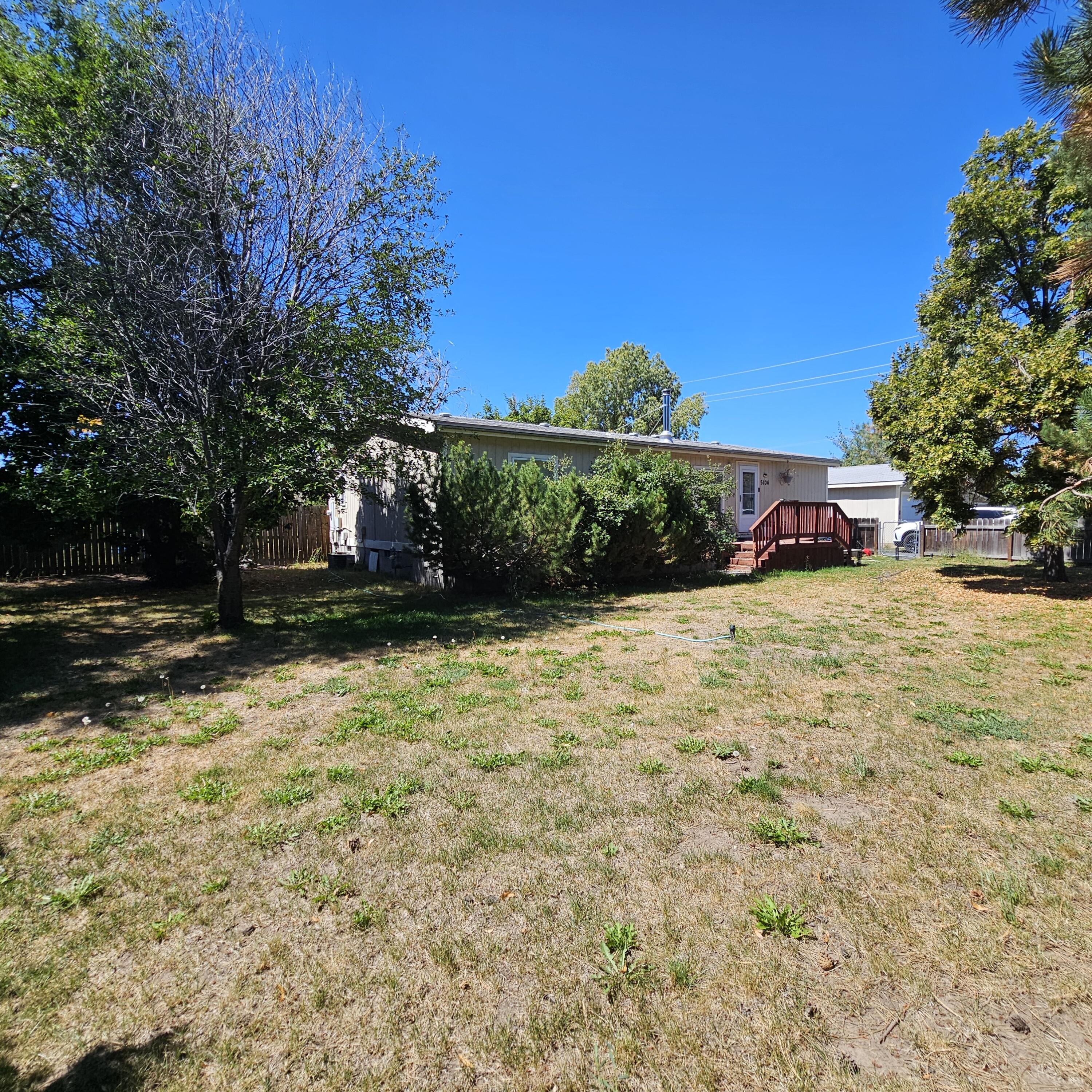 Charming 3-bedroom, 2-bath manufactured home on a .60-acre lot with mature trees, including fruit trees, and plenty of space for a garden. A willow and maple trees shade the deck and the house, creating a peaceful outdoor retreat. The detached oversized 30x32 garage is wired for 220 and includes a workbench and shelving, while the storage shed with power and lights offers extra room for toys or tools. Ample graveled parking provides space for RVs with a convenient power hook-up. Inside, the open living area flows into a kitchen with a large pantry. The primary suite features a walk-in closet, and the laundry/mudroom connects directly to the back deck. LVP flooring runs throughout with carpet in the primary bedroom. A certified wood-burning stove adds warmth and character. Additional highlights include a drive-through gate, fully fenced yards, front-yard sprinklers, double garage doors, and KID irrigation.