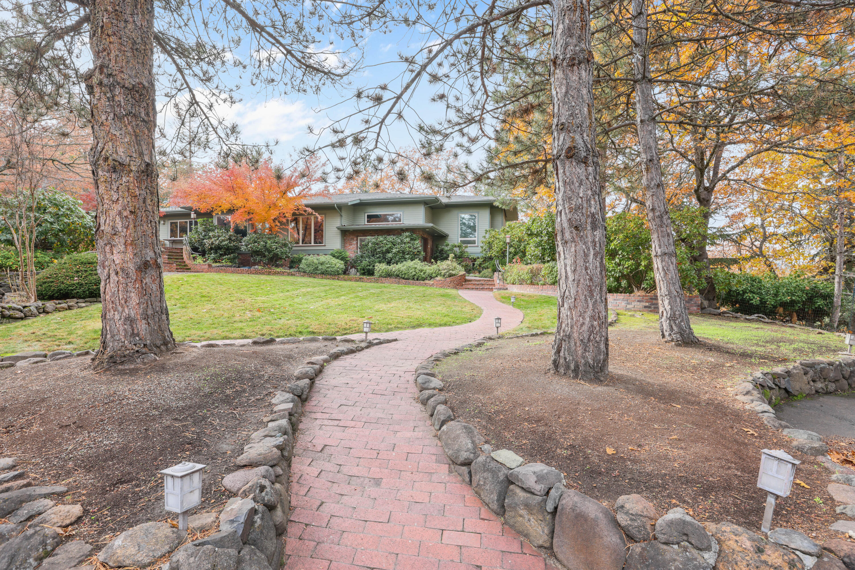 Delightful home on 0.86 acres with custom details throughout. A spacious split-level entry welcomes you into the main living area featuring the living room, dining room, great room, kitchen, and primary suite wing. The cook's kitchen with island and skylight opens to a warm great room with fireplace and breakfast nook, while the formal living and dining rooms capture stunning views of the rock-walled gardens, valley, and mountains. The primary suite includes an adjoining den or nursery, and a second bedroom suite offers excellent guest space. A large laundry room with access to the back patio and hot tub, plus a guest half bath, completes the upper level. The lower level is ideal for multi-generational living with a family room, two bedrooms, full bath, and hidden wine cellar. Outside features multiple patios, Zen-like spaces with water features, mature landscaping, a children's playhouse, a garden shed, and a detached two-car garage. Private, serene, one of a Kind, Must Tour!