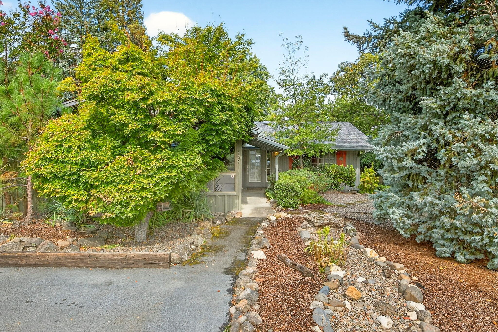 Welcome to this beautifully maintained single-level home, tucked away in a private, woodsy setting. Built in 1963 and thoughtfully updated, it offers the perfect blend of vintage charm and modern comfort.
Inside, the bright kitchen features vaulted ceilings, a skylight, and stainless steel appliances. The living room is warm and inviting with a cozy fireplace, vaulted ceilings, and engineered wood floors—an ideal space to relax or gather with loved ones. The primary suite includes a convenient walk-in closet and a custom en-suite bath with a tub and shower.
Outdoors, you'll appreciate the low-maintenance yard and tranquil atrium with a lovely water feature—a peaceful retreat to enjoy at any time of day.
Just minutes from downtown Ashland, this charming property combines peace, convenience, and timeless style. Don't miss this opportunity to own this charming piece of Ashland!