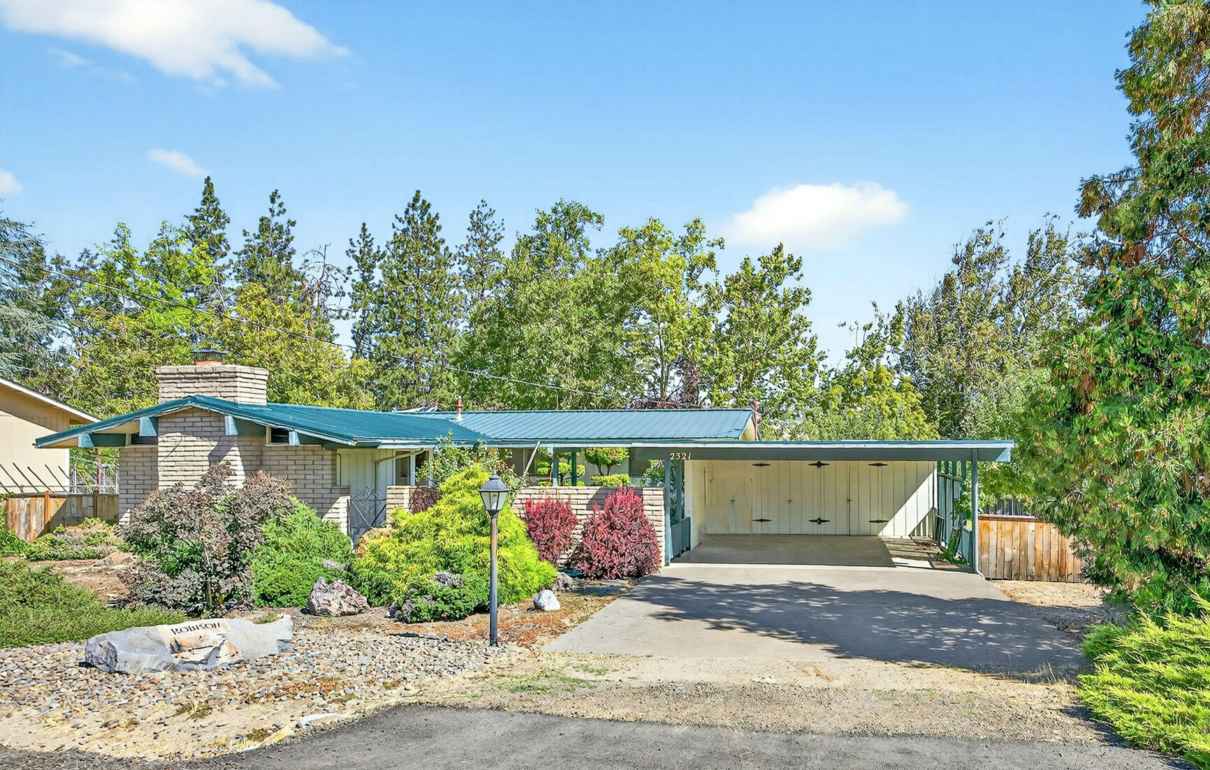 Located in a wonderful south Ashland neighborhood, this single-level house offers a comfortable and versatile living space. It features 3 bedrooms and 2 bathrooms, and at 1400 sq. ft., the L-shape floor plan makes it live larger. The living room is particularly inviting with its wood-clad vaulted ceiling, built-in bookcases, and a cozy fireplace, which together create a lovely blend of classic charm and modern appeal. Excellent views of the hills from the dining area and primary bedroom. A generous .24 acre lot with a welcoming entry courtyard, attached carport with storage, and a fenced backyard. The yard is truly a highlight, featuring mature fruit trees and benefiting from TID irrigation rights, which provides opportunities for gardening and development of engaging outdoor spaces. This home is an excellent value in a very sweet setting.