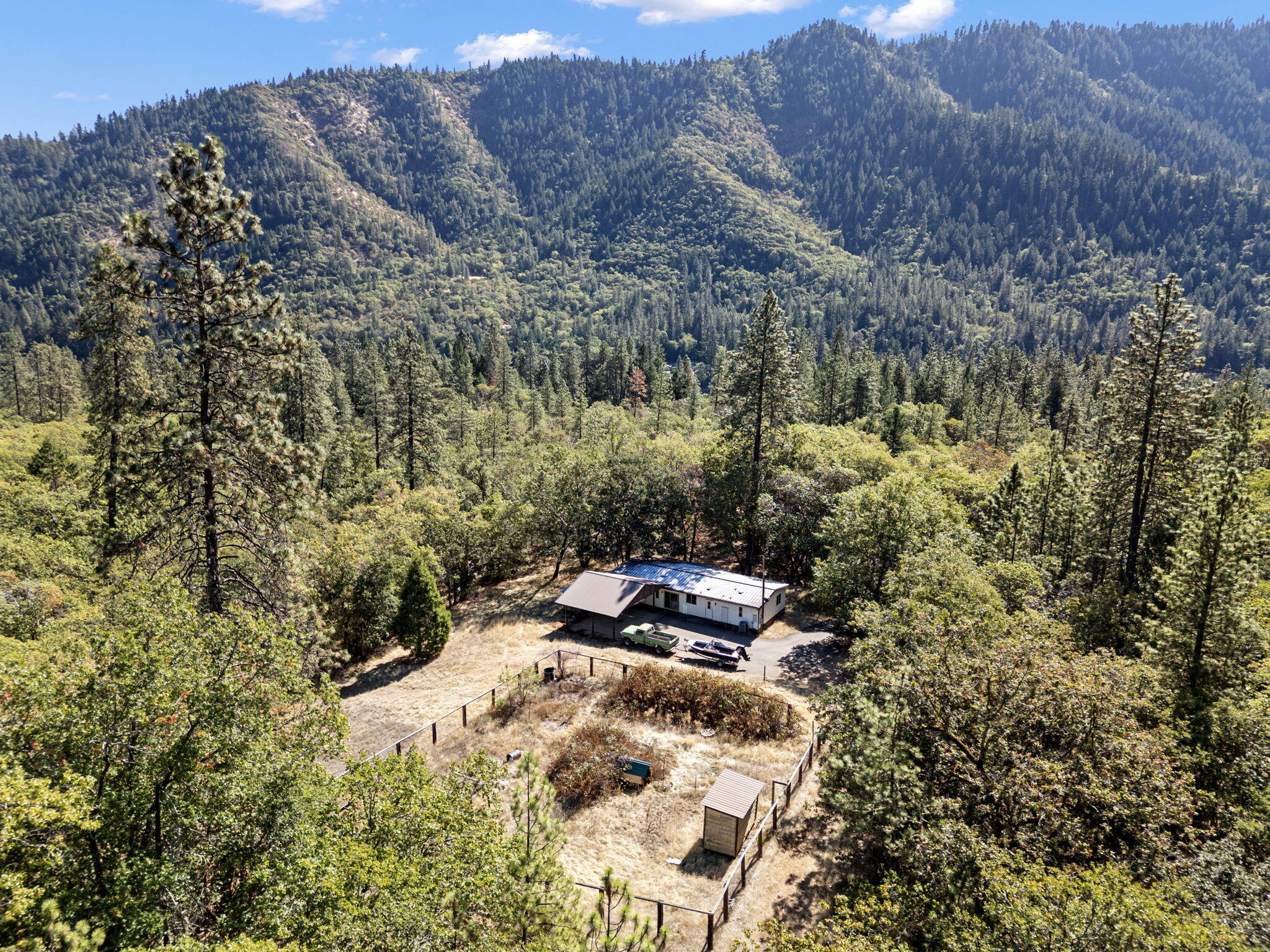 PRICE REDUCTION/ MOTIVATED SELLER!! Don't forget to watch the video attached to this listing to see the beauty of owning nearly an entire mountain with this private 96-acre property offering stunning views and endless potential. There is lending available for this property. The 1,783 sq. ft. home is ideal to update, replace, or live in while building your dream home. Features include a fully fenced ¼-acre irrigated garden, year-round stream, 2,000+ sq. ft. barn/workshop, hog pen, large dog run, RV hookups, and multiple carports. Property spans both sides of the freeway, including land on the side of the scenic Rogue River perfect for recreation or future development. Enjoy merchantable timber, a strong well, and a long paved and gated driveway leading to your serene mountain getaway. A truly unique opportunity in Southern Oregon! Buyer to verify all details; showings by appointment only, please do not walk on decks, as they may be unstable in spots.