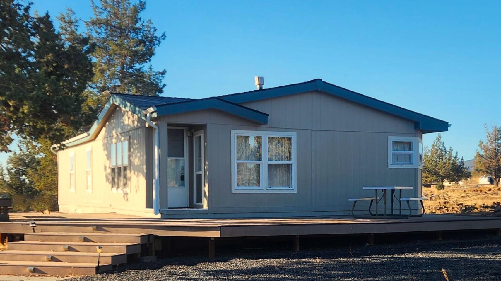 Great opportunity to own 5 acres in 3 Rivers, move-in ready, fabulous rim views of the Cascades, Smith Rock, and Big Canyon. 2 generous bedrooms, 2 full baths, open concept w/great room, kitchen & dining w/tons of built-in storage plus propane fireplace (rented tank) for heating. Laundry room with additional man door  leading to large wrap-around deck for entertaining and relaxing with friends and family.  All appliances and furnishings included at no stated value. Solar owned system includes 500 watts of PV panels, inverter/charge controller and new batteries in 2025. 1200 gallon cistern in separate-insulated building, outhouse, storage building and mechanical building plus new 30 year roof installed recently. This one won't last long with all these features and an affordable price. Call your favorite agent to book a viewing today.