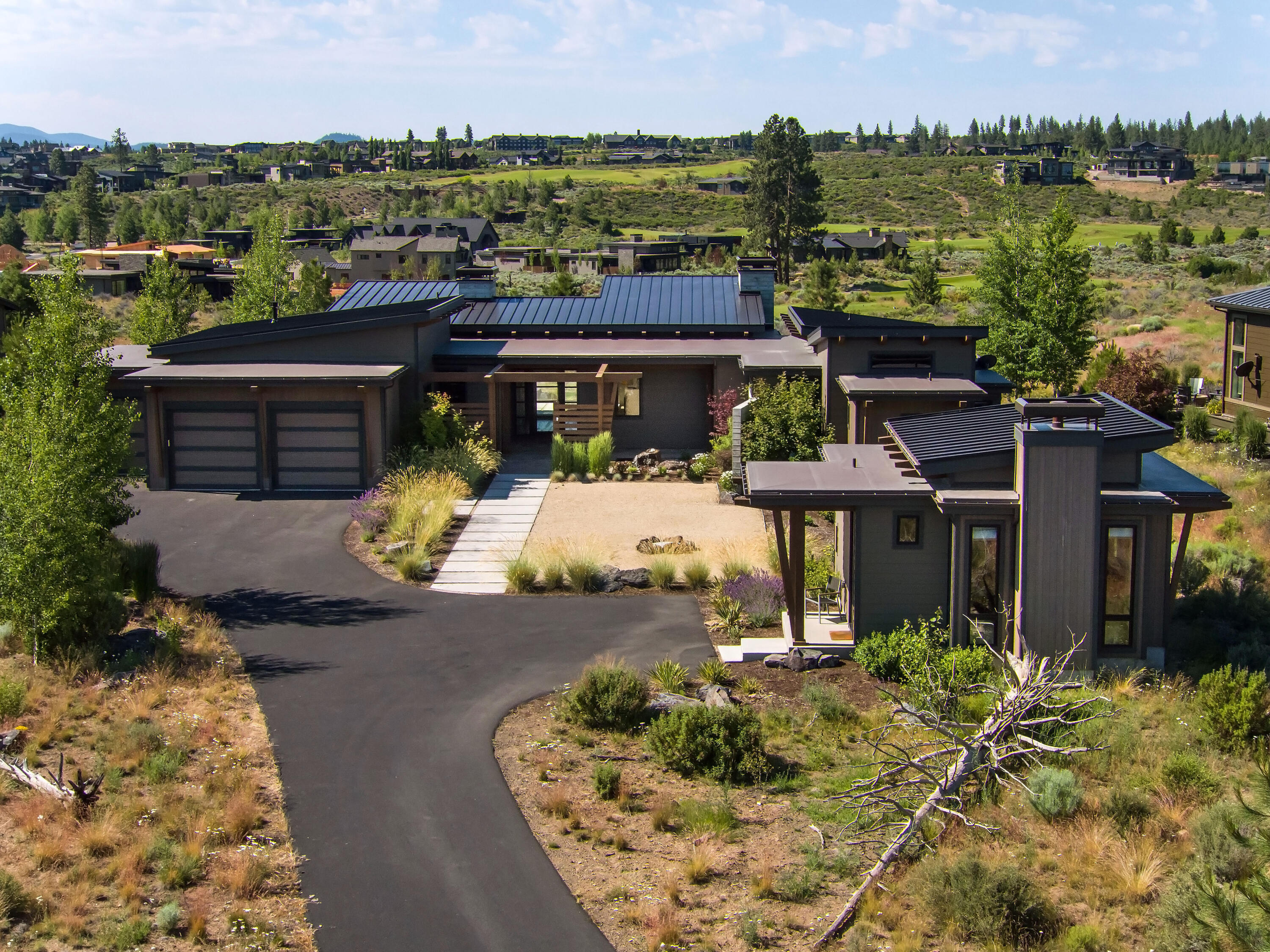 Take in the incredible mountain views and luxury resort living in this single-level modern home in Bend! With a spacious, open floor plan and natural light throughout, the contemporary design and impressive finishes, including white oak floors, exposed beams, Board form concrete walls & wood burning fireplace, hold both a peaceful sanctuary feel as well as perfect gathering spaces. The gorgeous primary suite is complete with access to the covered patio with expansive views and outdoor gas fireplace. On the opposite wing, the additional bedrooms, all with en suites, will offer all of the overnight quiet and privacy desired. Large office in the main home and the added detached casita are ideal remote workspaces, home dens, or studies. Low maintenance landscaping surround this gorgeous house located in the gated cul de sac community in Tetherow that borders the Deschutes National Forest, with perfect indoor and outdoor areas for your Central Oregon living experience at its very finest